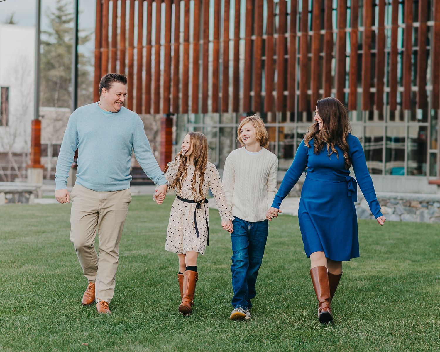 A group of people walk together across a grassy lawn wearing coordinated blue and khaki outfits.