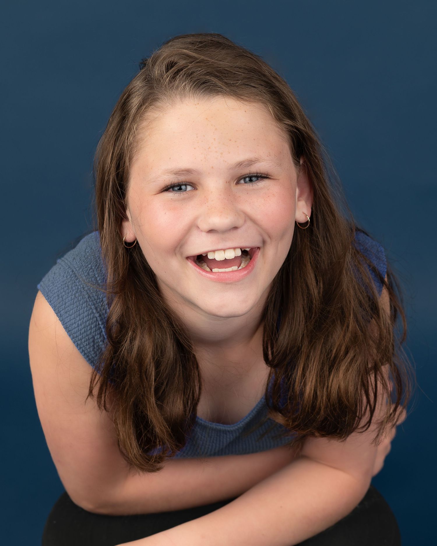 Child with brown hair smiling joyfully in a sequence of poses against blue background.
