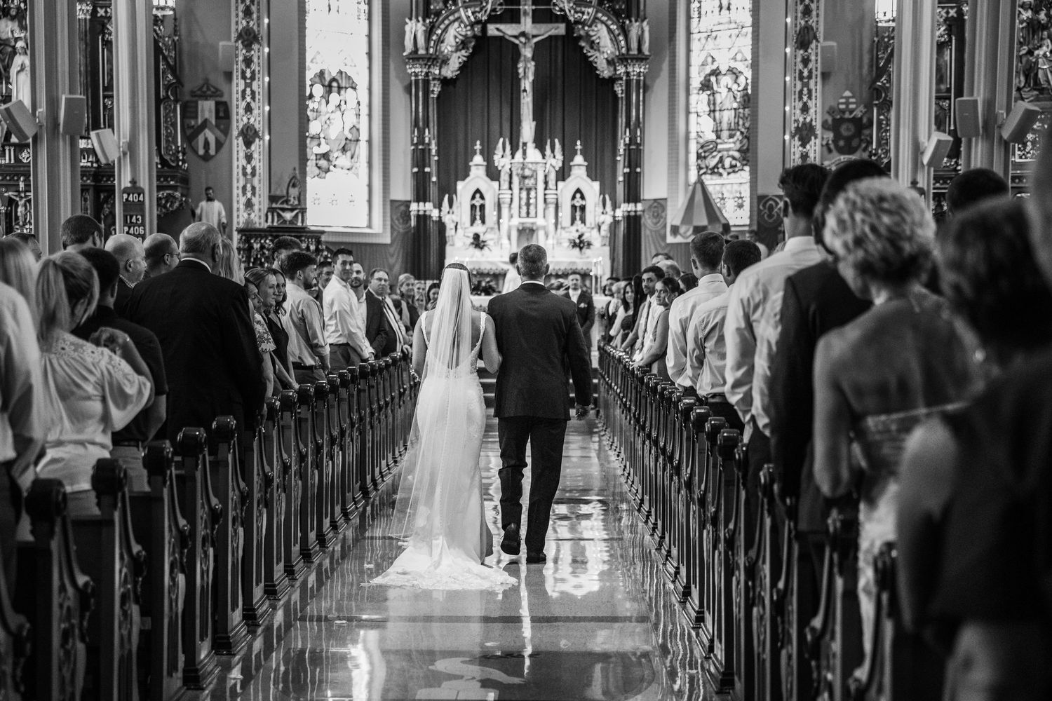 A wedding ceremony takes place in an ornate cathedral with guests seated in wooden pews and a couple at the altar.