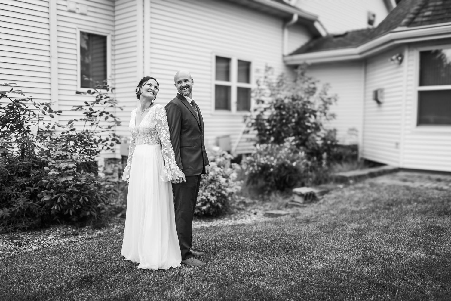 Black and white photo of bride and groom standing in a private garden.