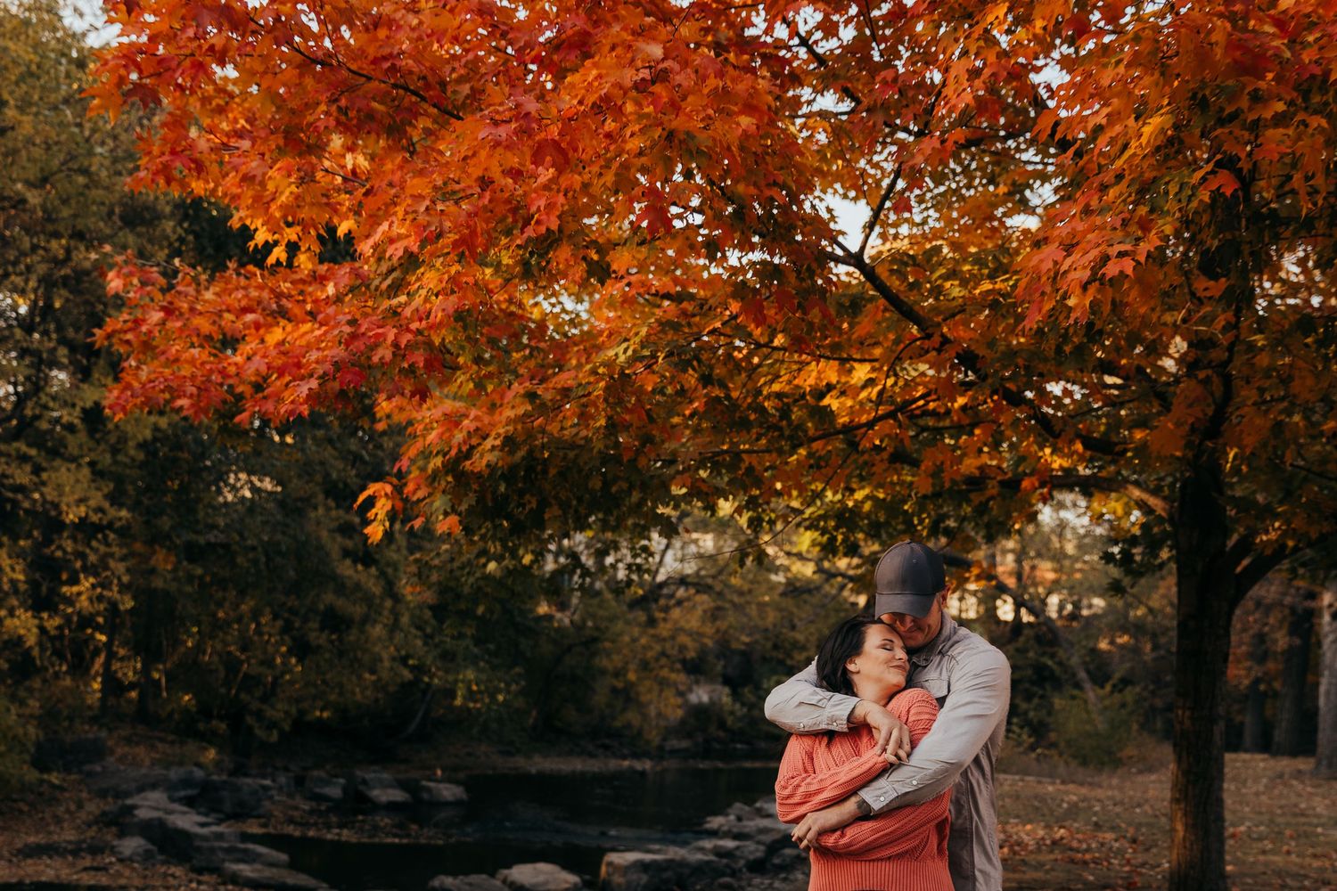 Romantic couple photoshoot under vibrant red and orange fall foliage.