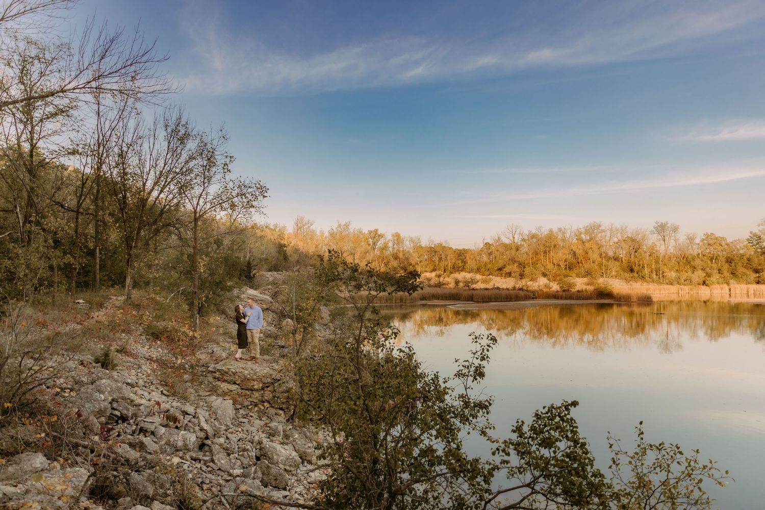 Scenic panoramic view of a calm lake surrounded by autumn trees under blue skies.