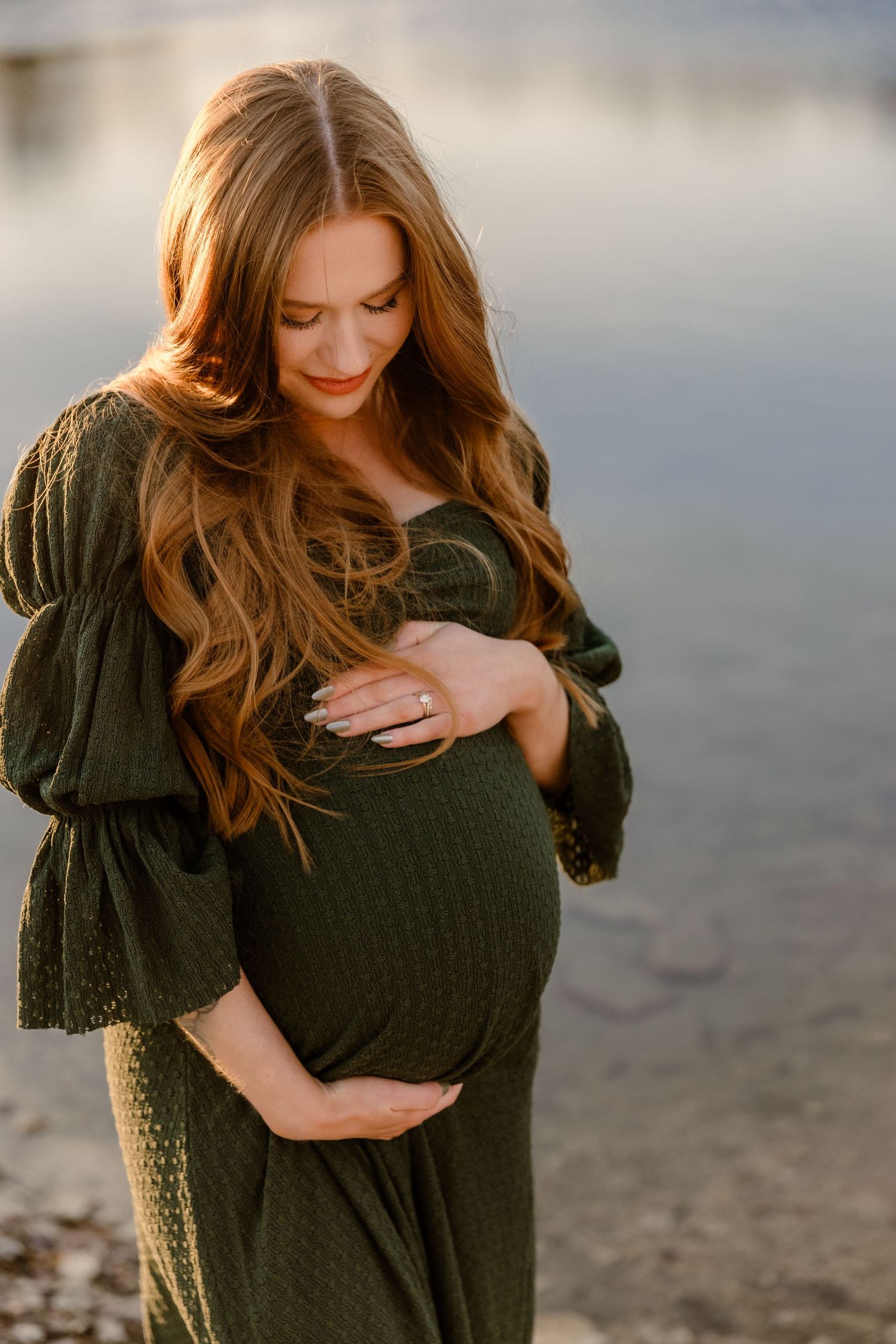 Woman in dark knit sweater poses thoughtfully during golden hour outdoor portrait session.