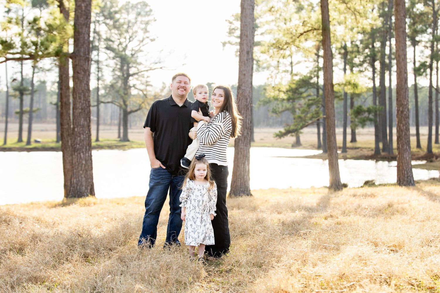 Romantic outdoor photo session among tall pine trees in natural lighting.