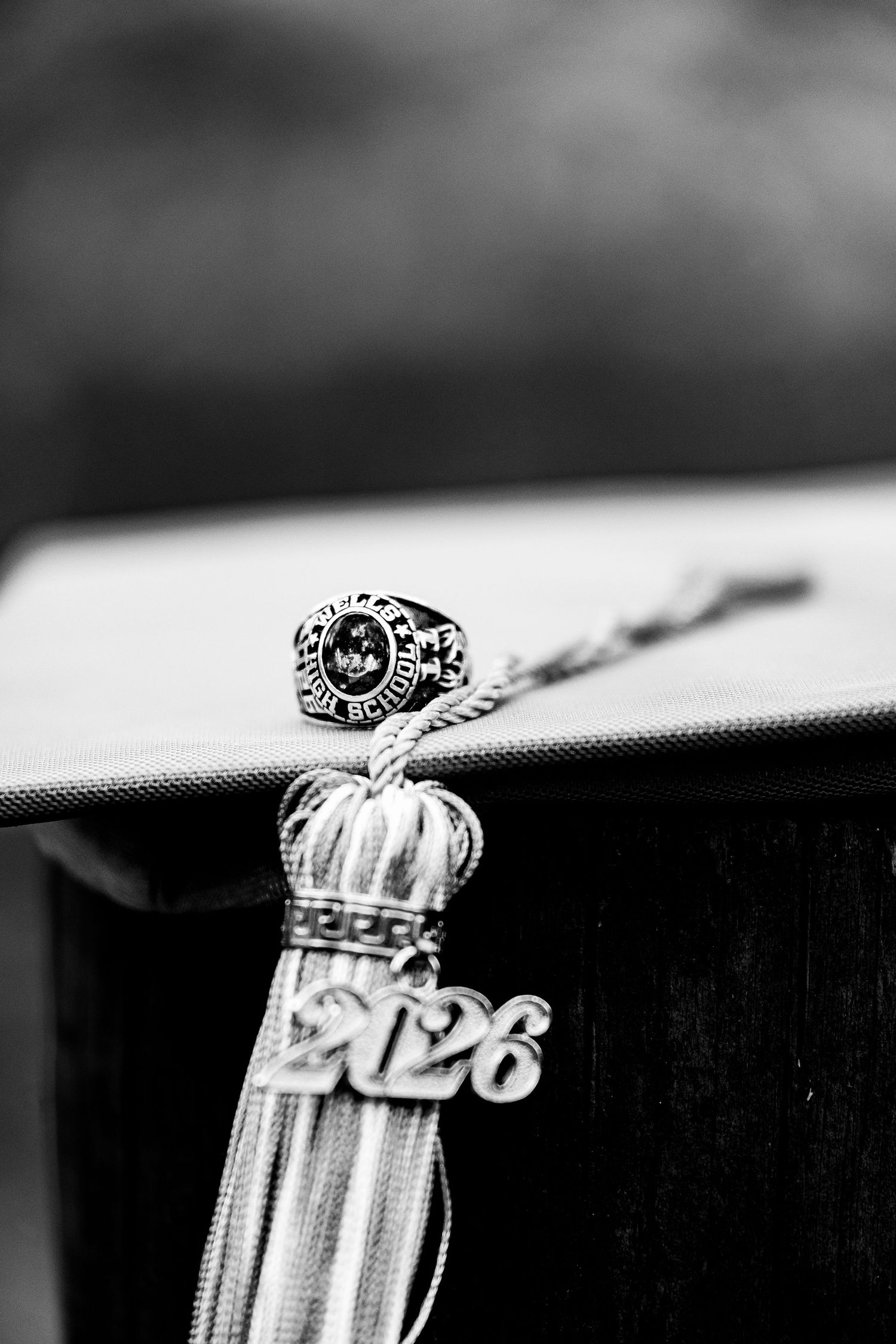 Black and white photo of a 2026 graduation cap tassel and class ring resting on a diploma.