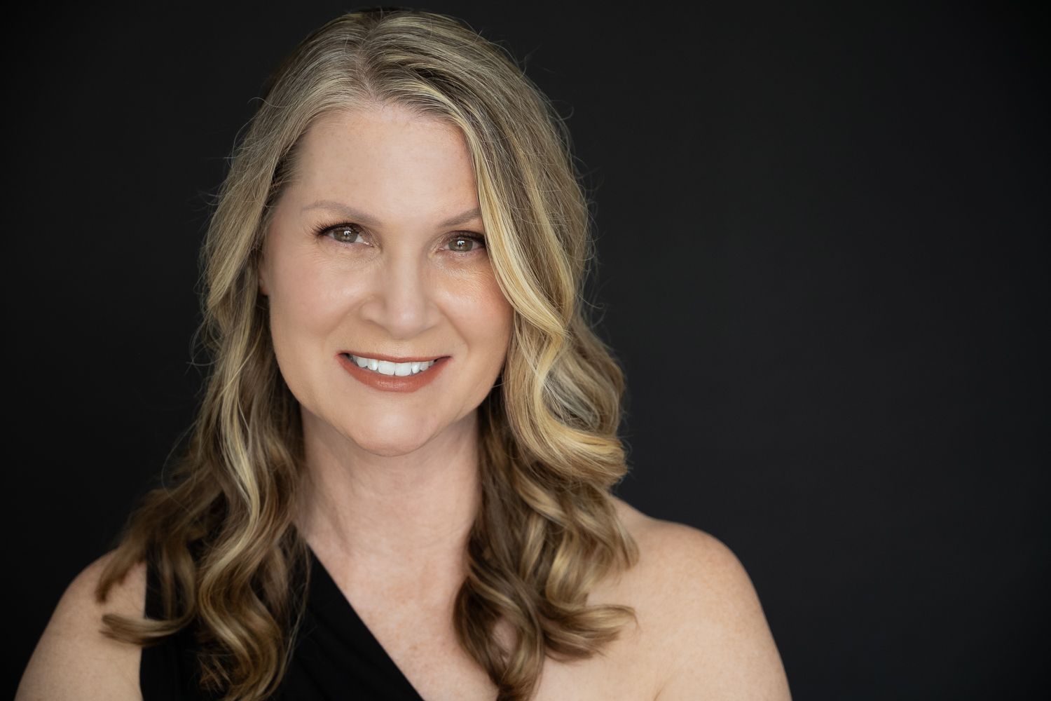 Professional headshot portraits of a person with wavy blonde hair against a dark background.