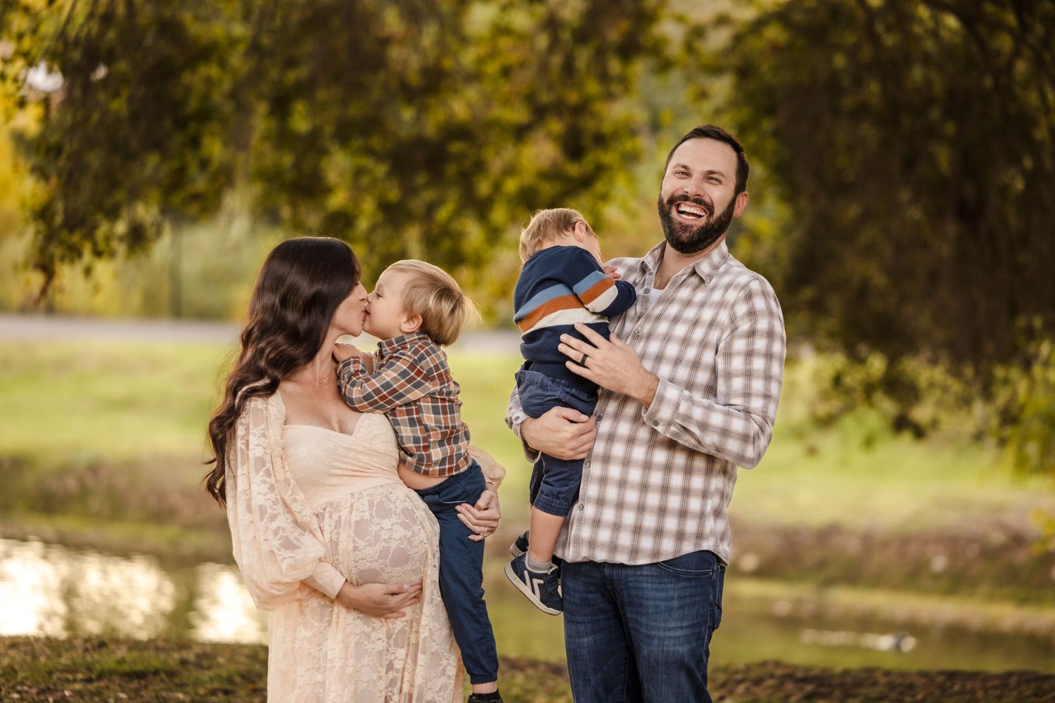 A happy family of four enjoys an autumn day together outdoors in a natural setting with golden sunlight.