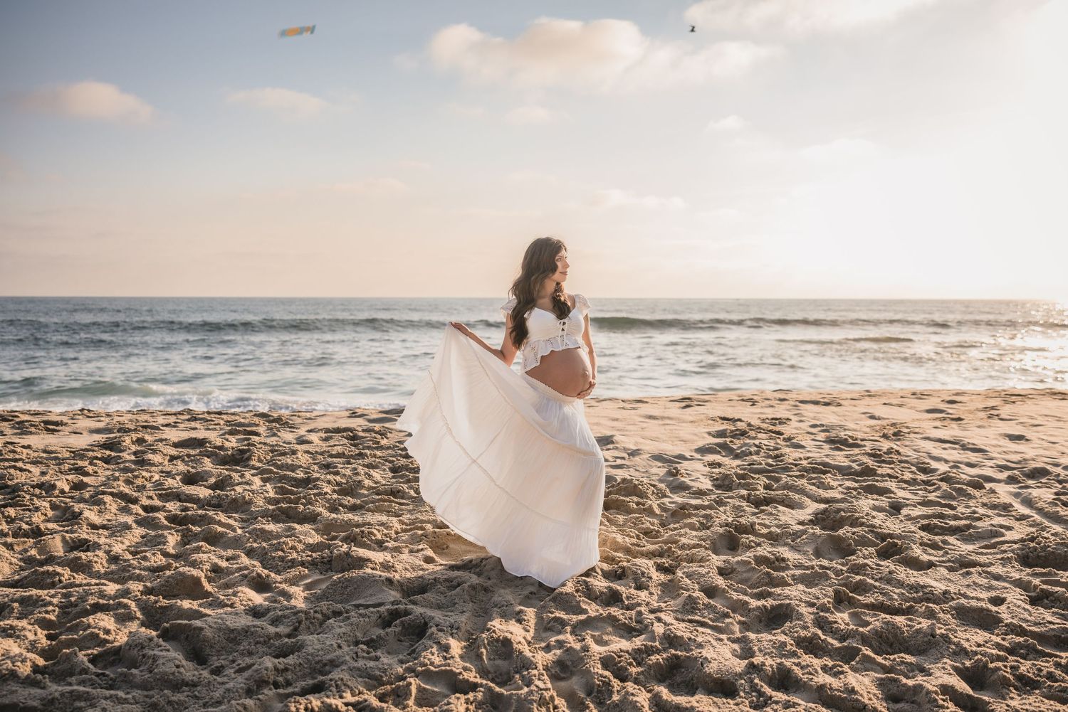 A sequence of photos showing a person in a white dress walking along a sandy beach during sunset.
