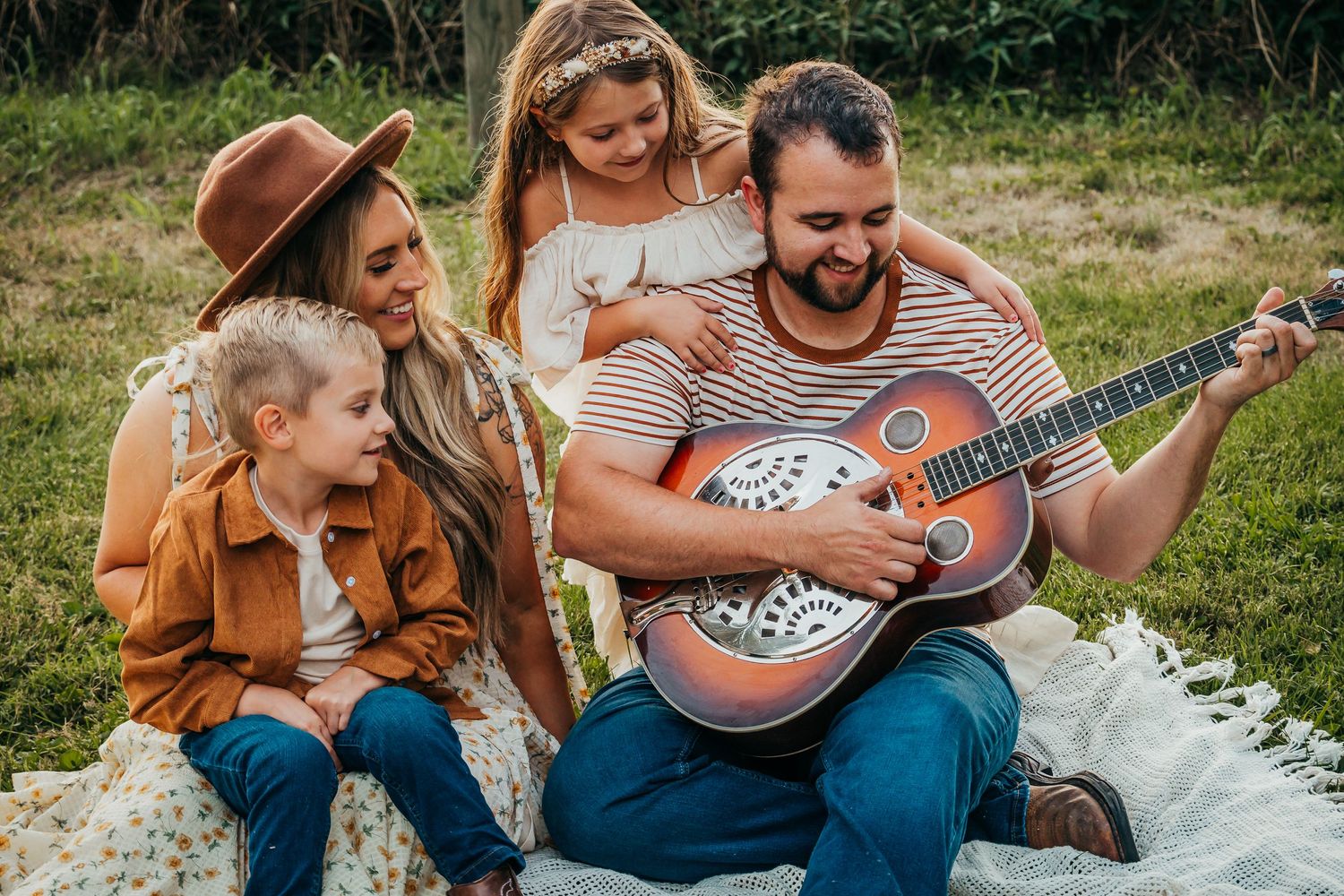 Family of four listening to dad play guitar