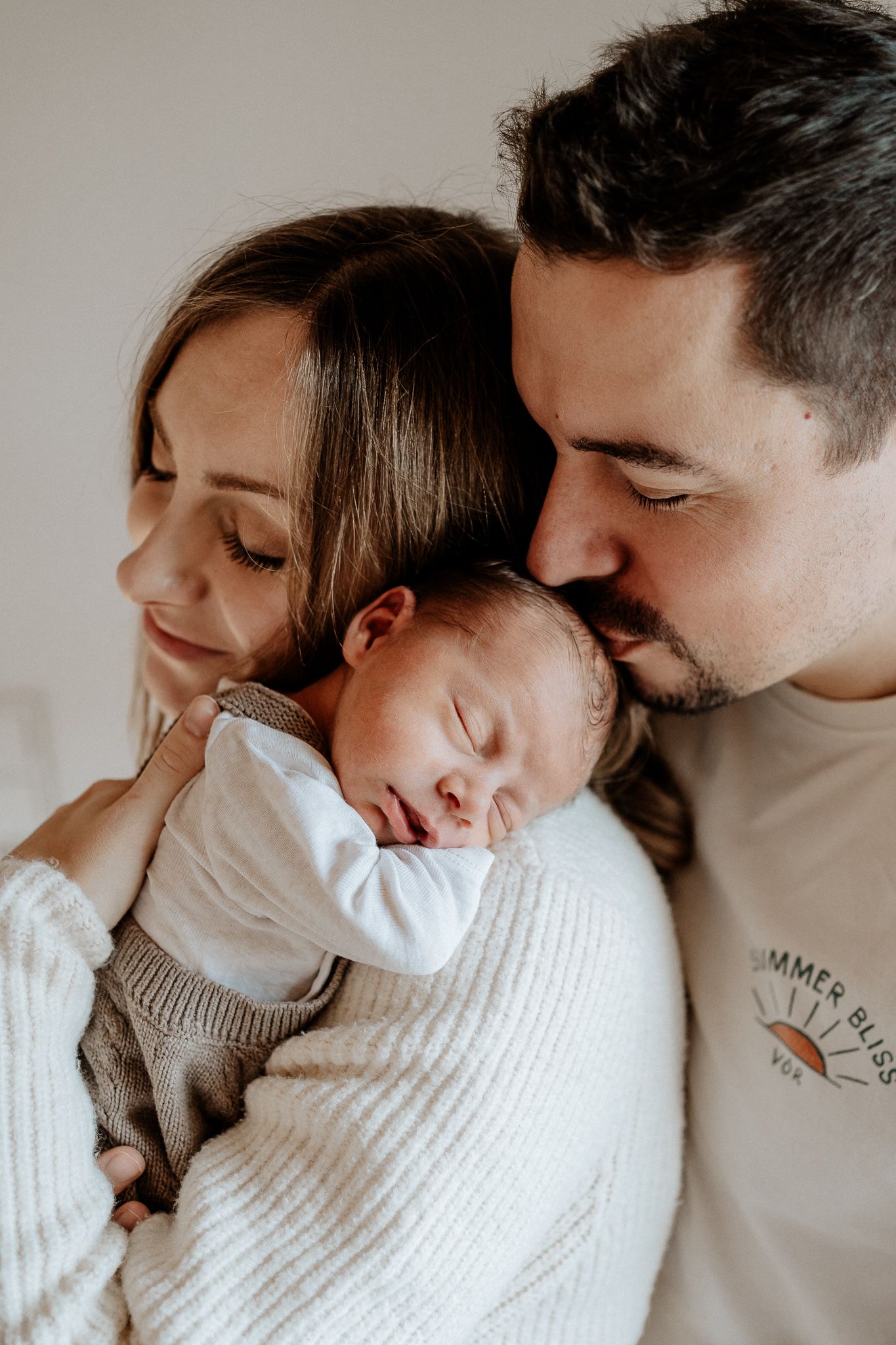 Eltern halten ihr Baby gemeinsam und genießen einen liebevollen Moment voller Nähe.