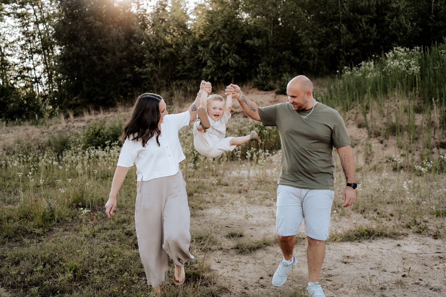 Familienfotos draußen – Eltern spielen mit ihrem Kind in natürlicher und entspannter Atmosphäre.