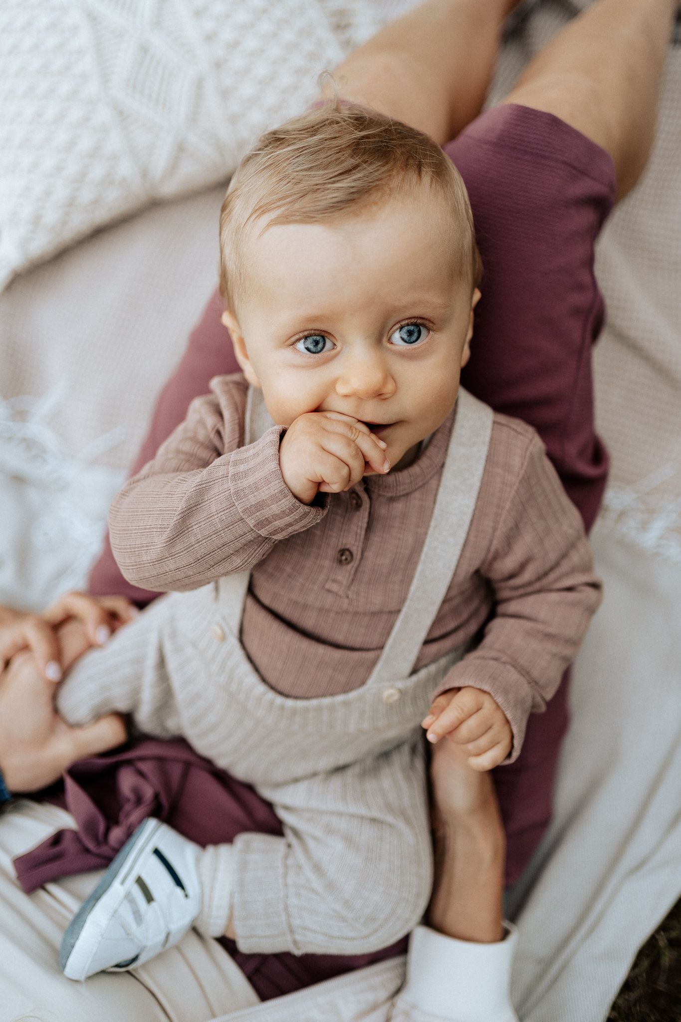 Kleines Baby sitzt neugierig da und schaut mit wachem Blick in die Kamera.