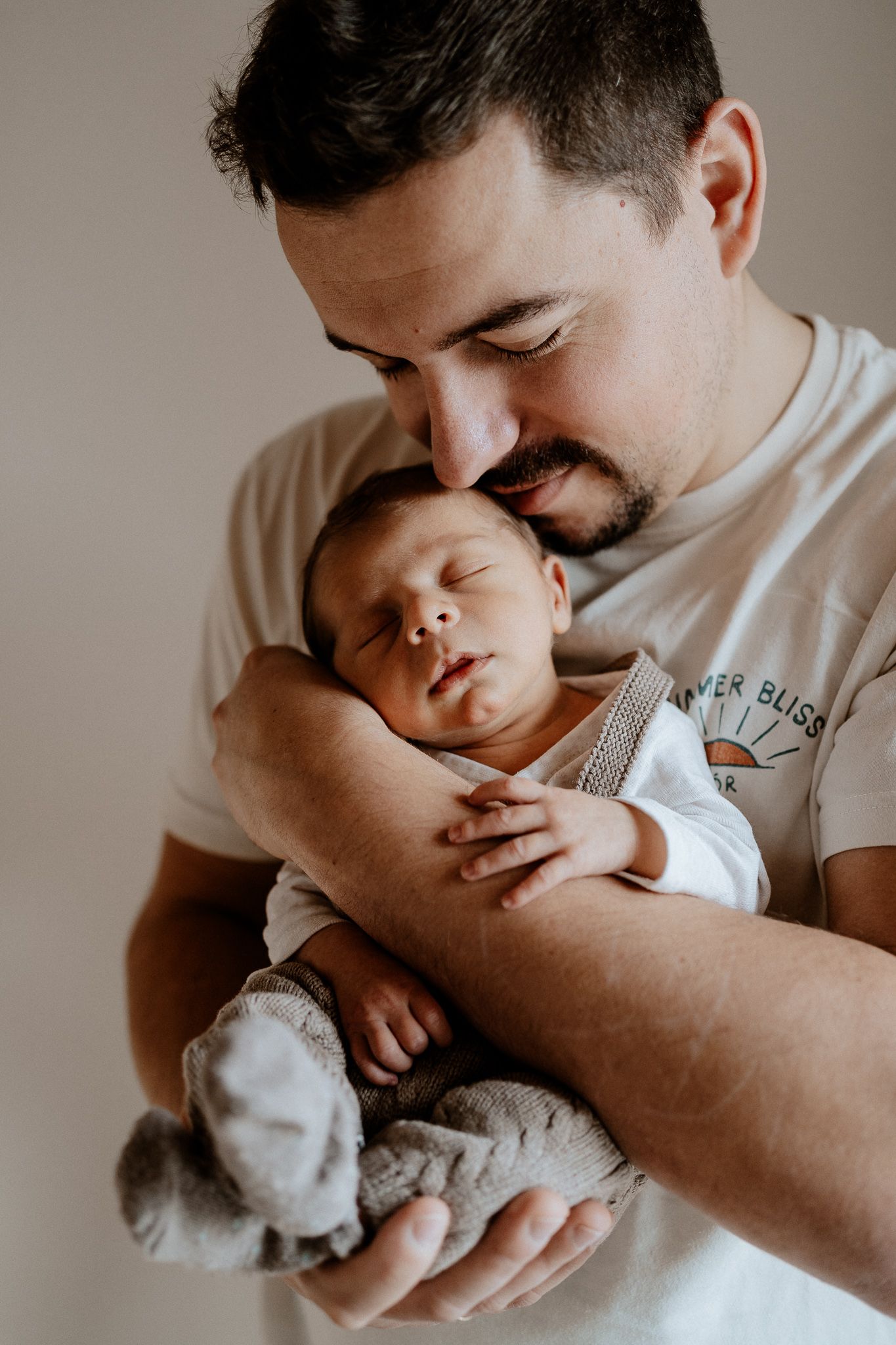 Vater hält sein neugeborenes Baby sanft im Arm – ein ruhiger und inniger Moment.