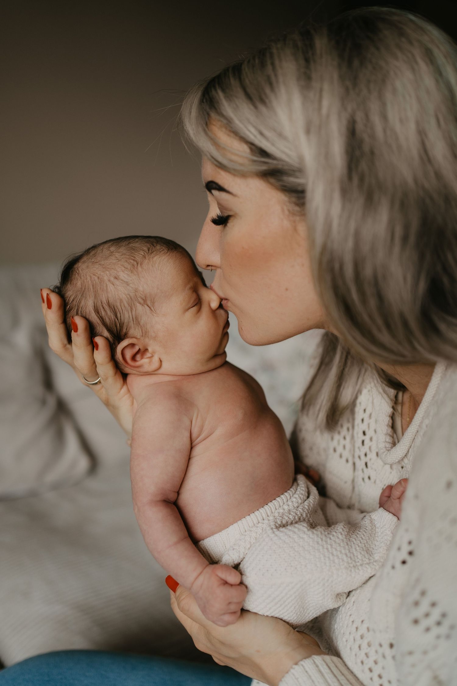Mama hält ihr frisch geborenes Baby in den Händen und gibt ihm einen Kuss auf die Nase