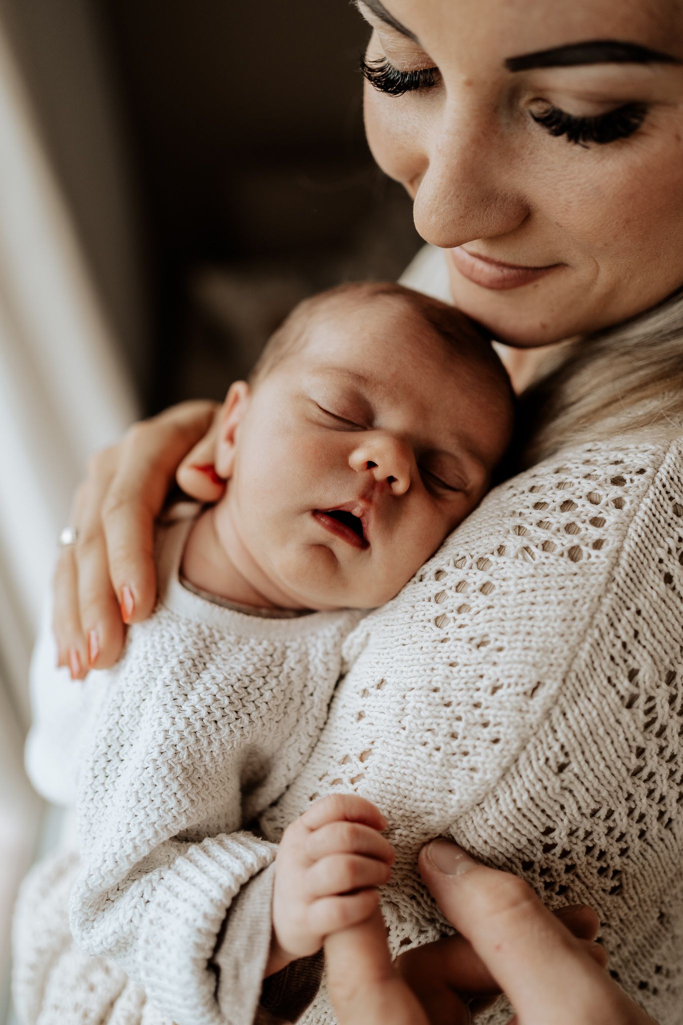 Mutter wiegt ihr neugeborenes Baby sanft im Arm – ein zarter Moment voller Geborgenheit.