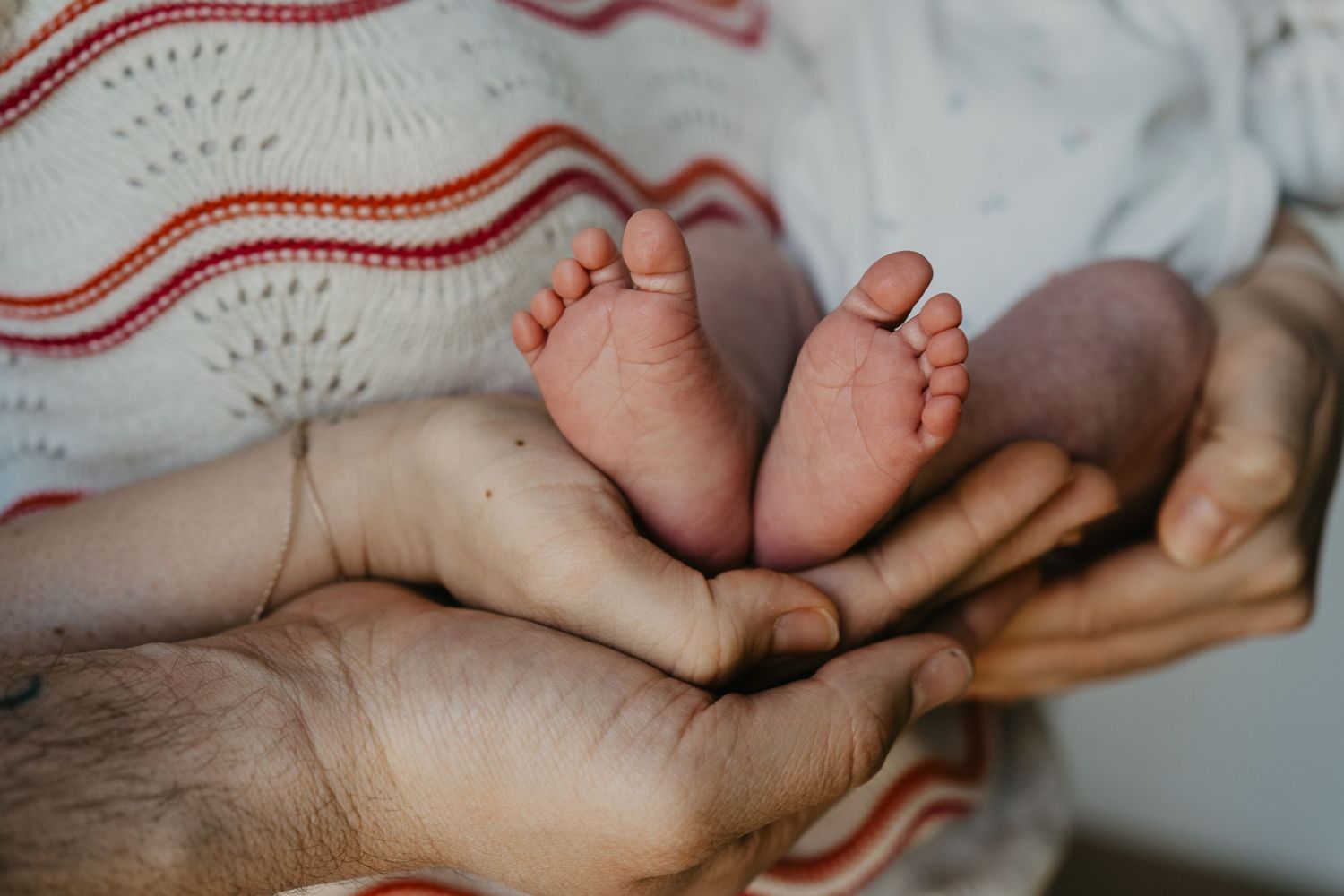 kleine, zarte Babyfüßchen, die von den Eltern liebevoll gehalten werden