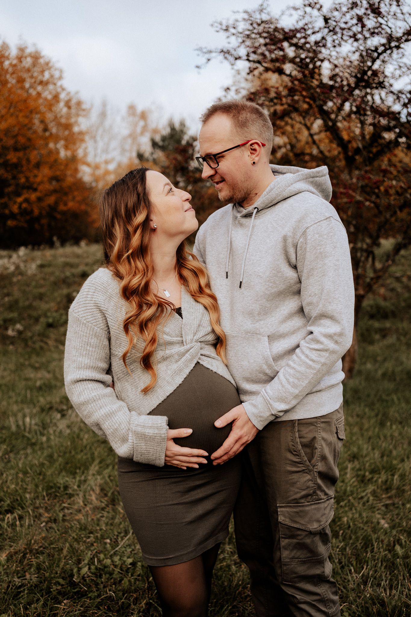 Natürliches Paarfoto während der Schwangerschaft mit Fokus auf den Babybauch in der Natur.