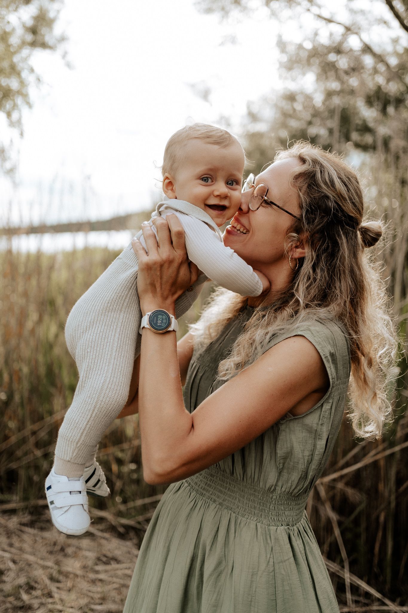 Mutter hebt ihr Baby hoch und lächelt es voller Zuneigung an.