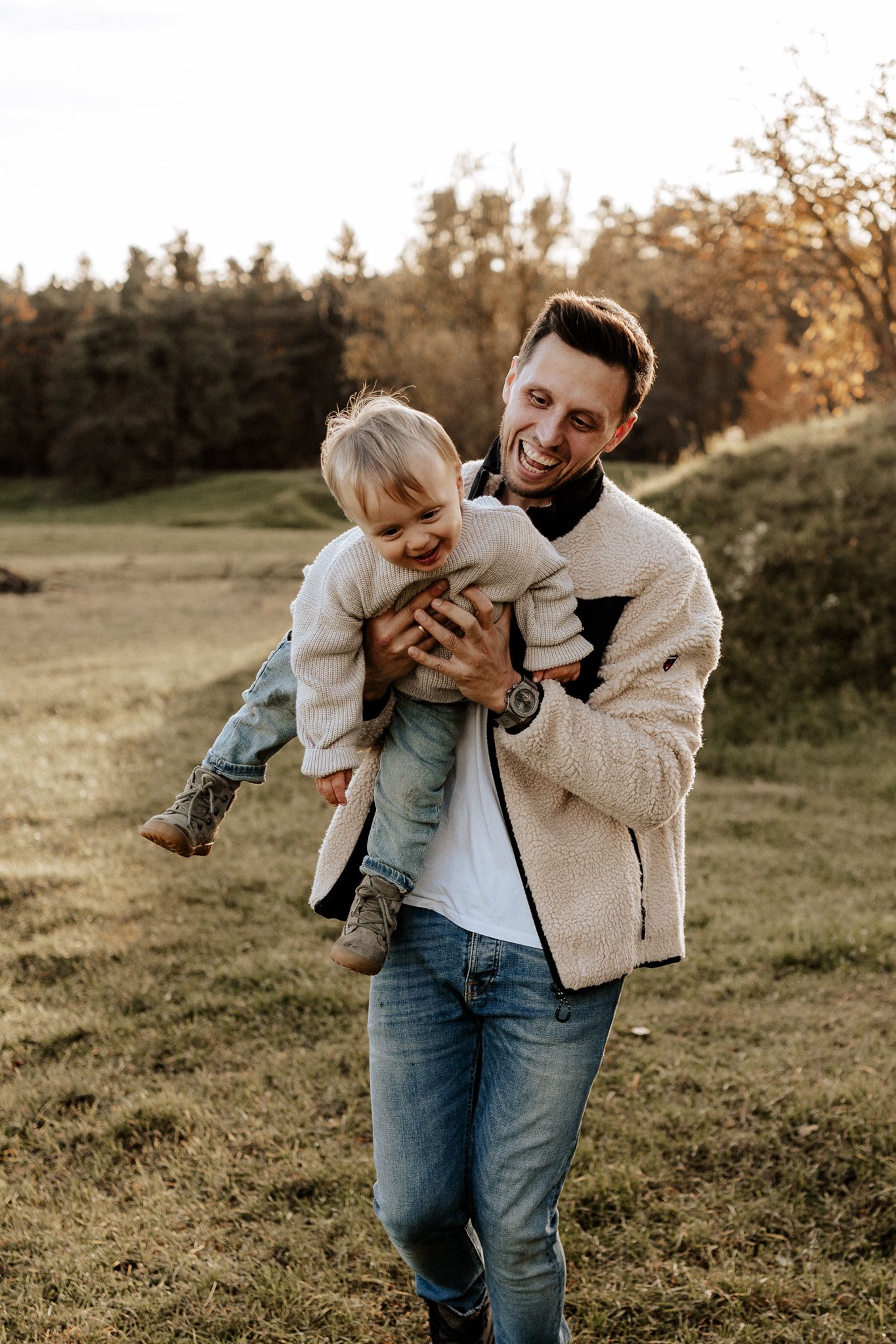 Vater trägt sein Kind lachend durch die Natur – fröhlicher und ungestellter Familienmoment bei einem Fotoshooting in Neumarkt.