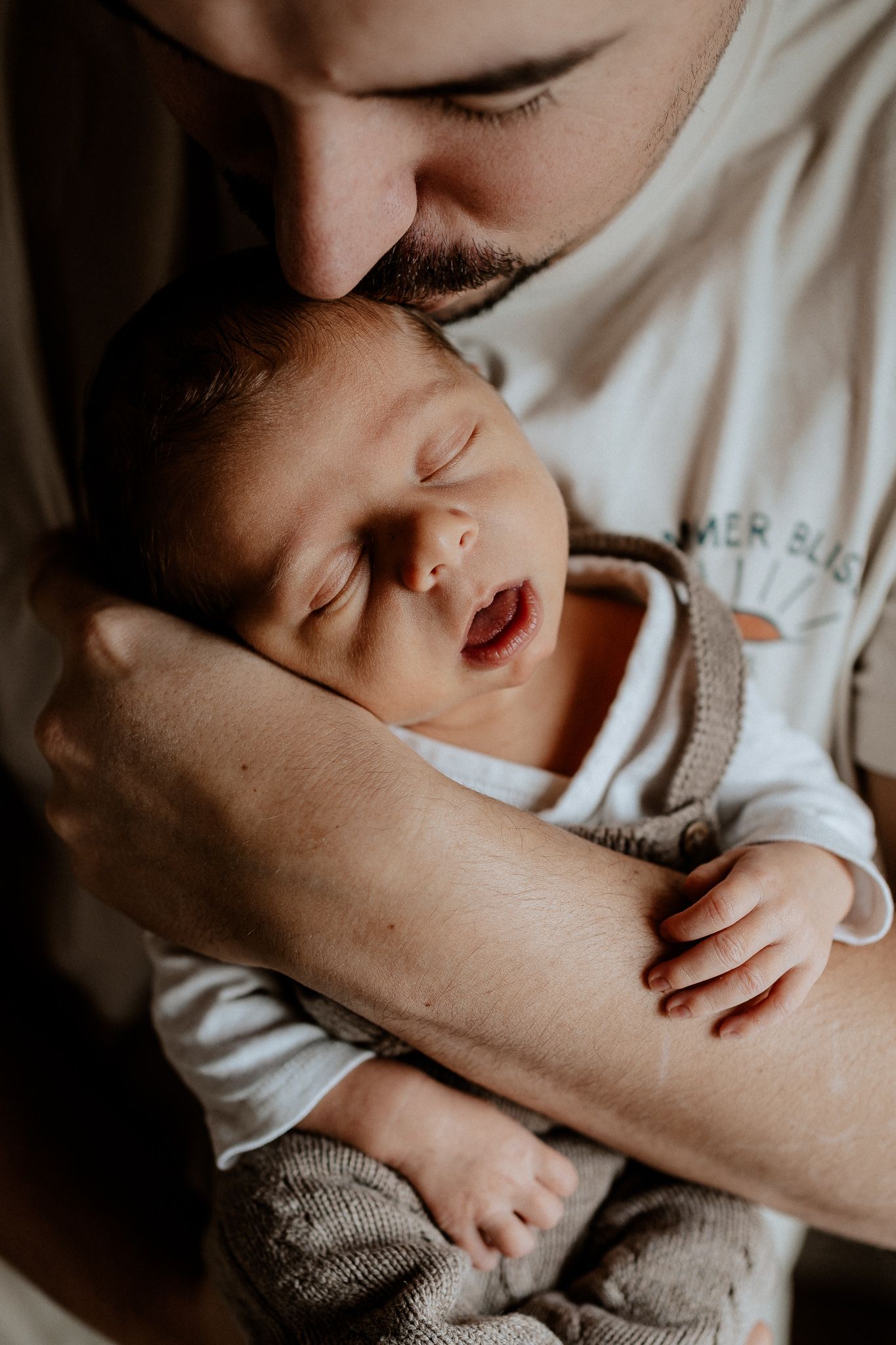 Emotionale Neugeborenenfotografie in Roth: Vater küsst sein schlafendes Baby liebevoll auf den Kopf.
