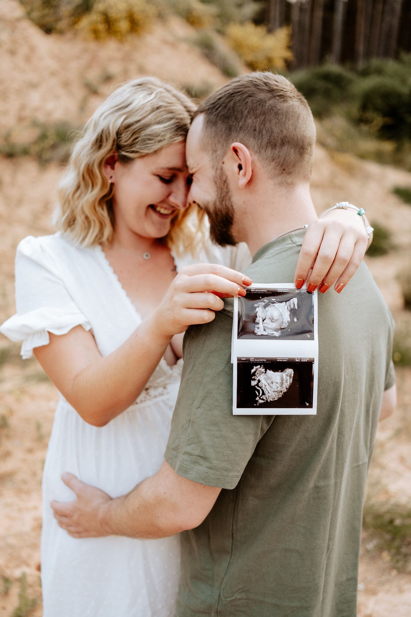 Babybauchshooting mit Ultraschallbild – glückliches Paar zeigt erstes Bild ihres Babys.