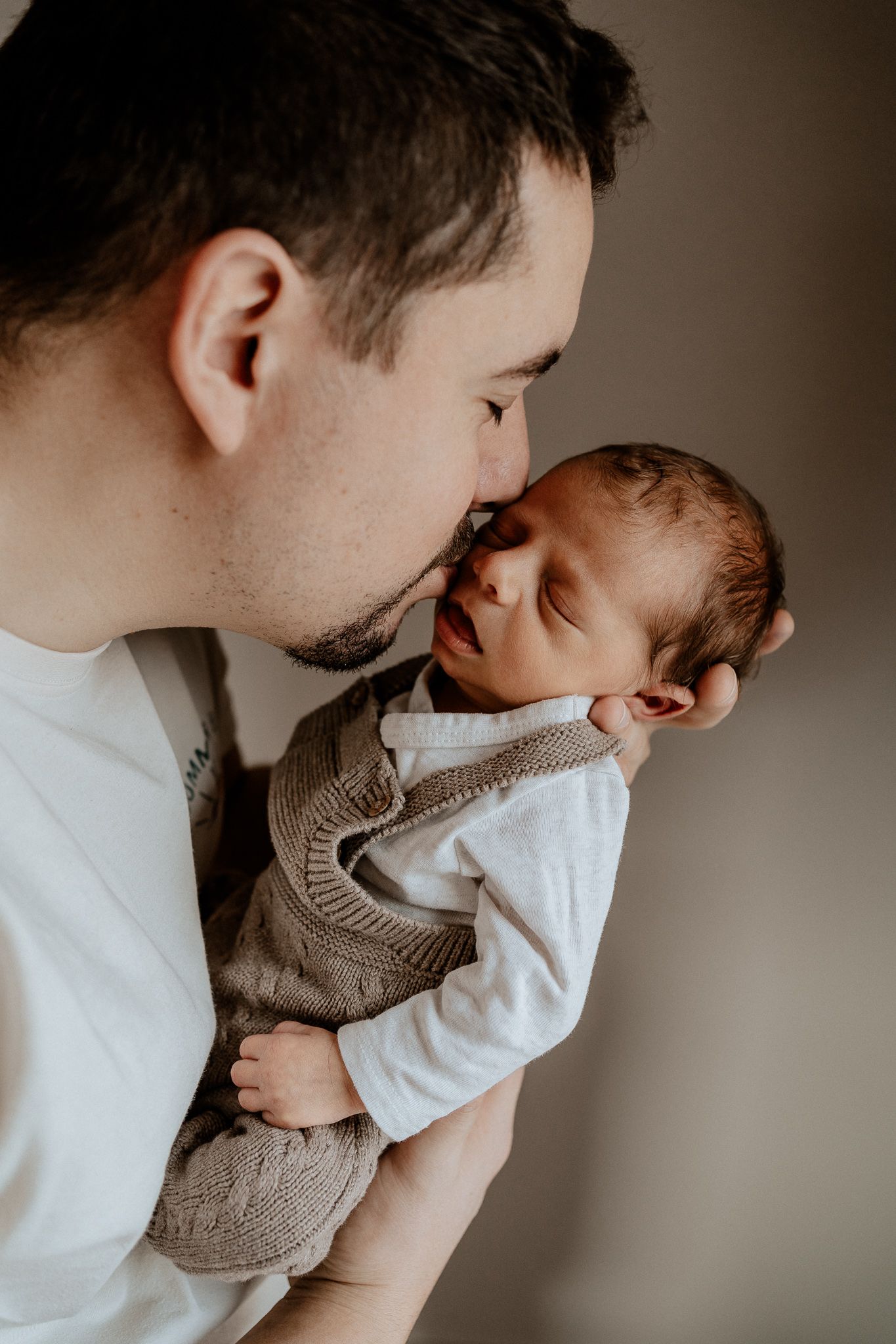 Vater hält sein Baby liebevoll im Arm und genießt einen ruhigen Moment.