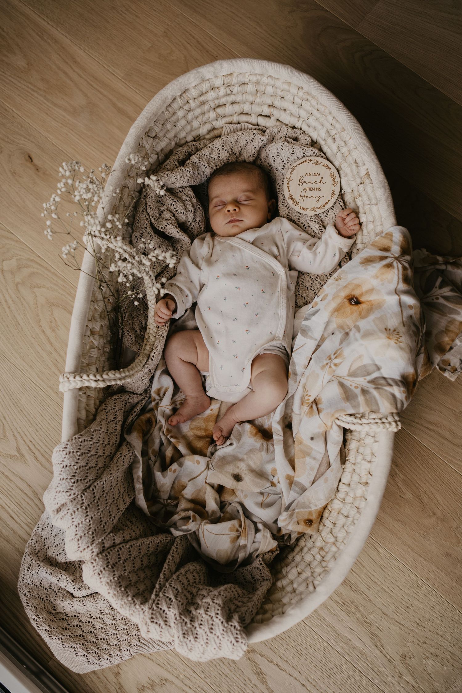 frisch geborenes Baby schläft zufrieden in einem Körbchen, umgeben von weichen Tüchern