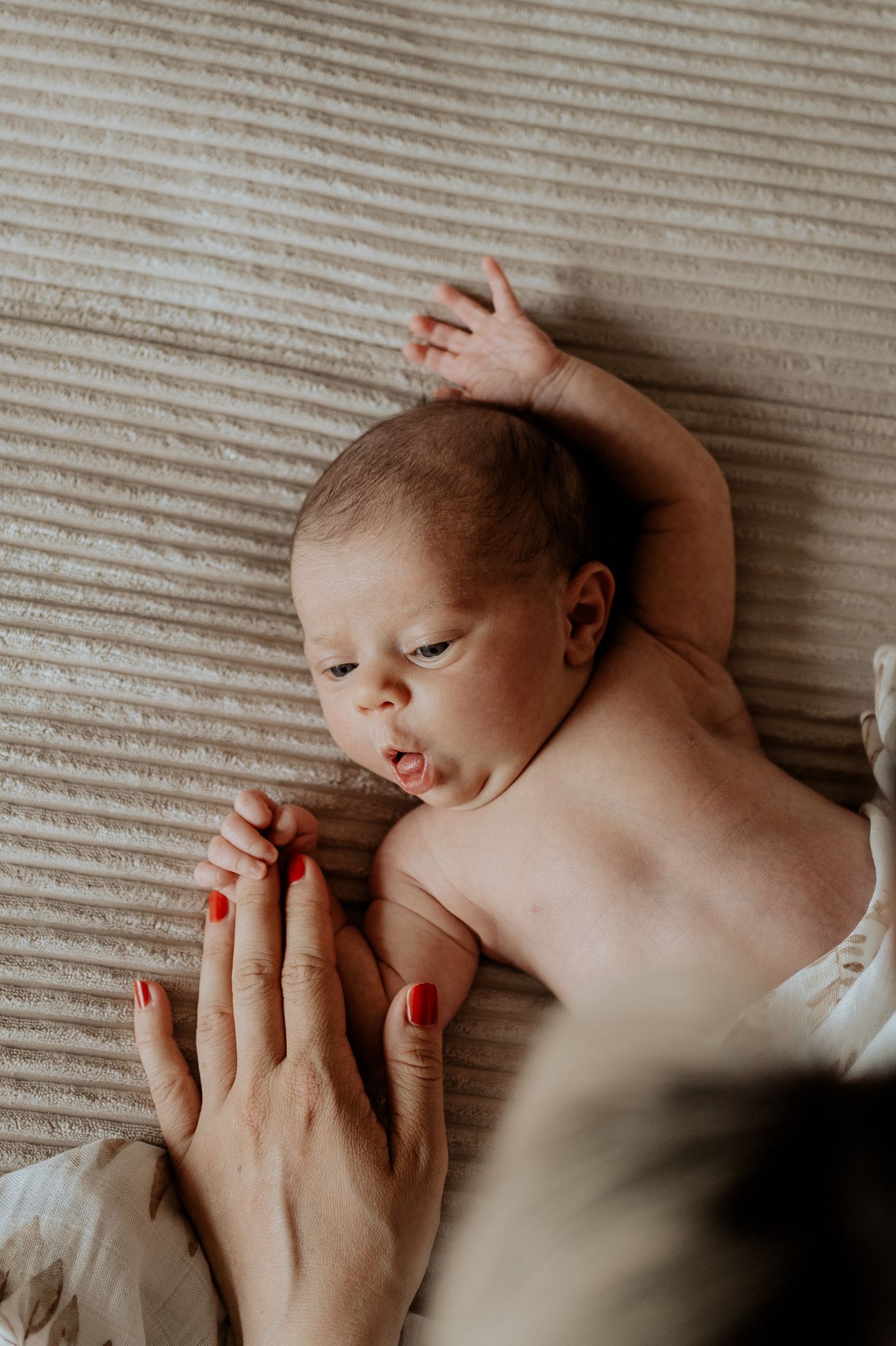 Baby hält sich an der Hand der Mutter fest – zarte Verbindung im Wochenbett.