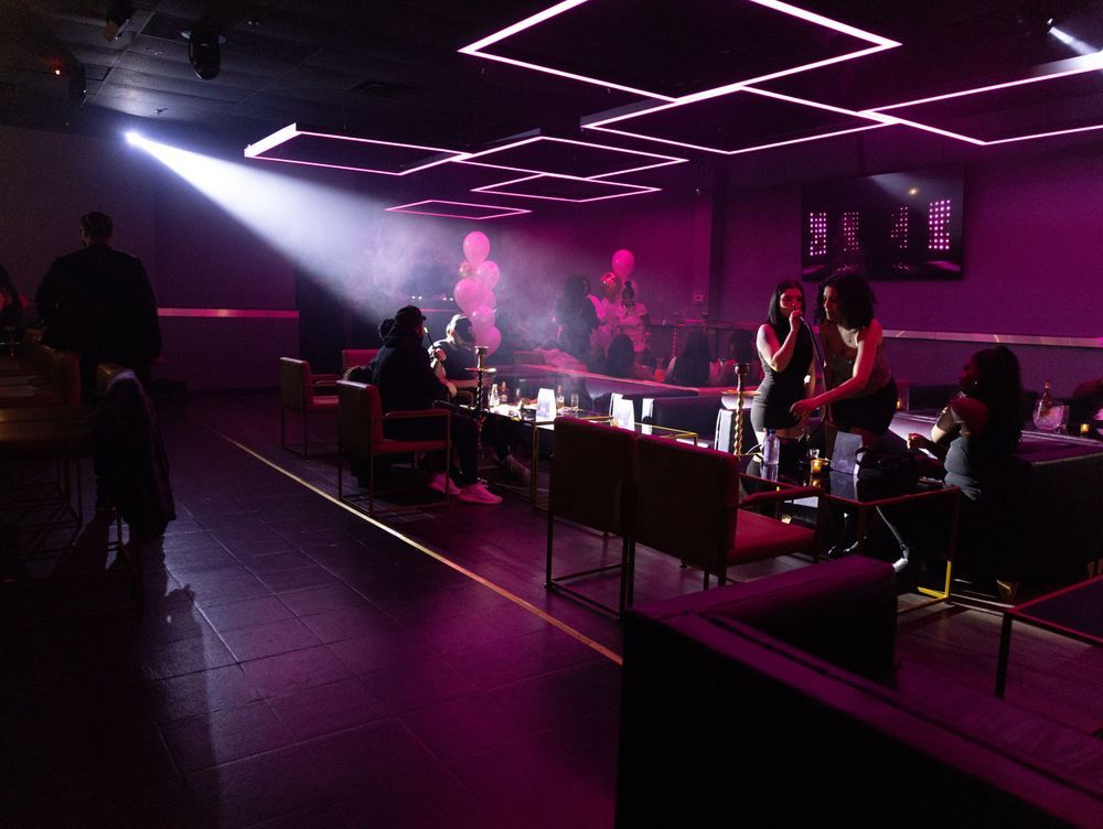 Modern nightclub interior with purple neon lighting and geometric ceiling design.