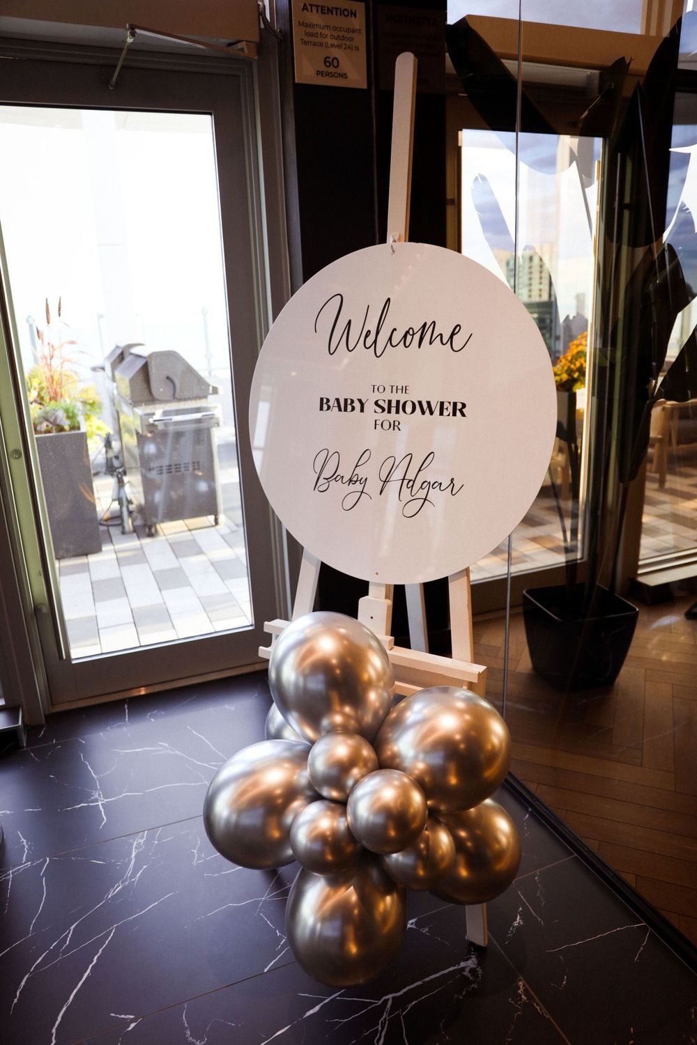 Welcome sign for baby shower with silver balloon arrangement at venue entrance.