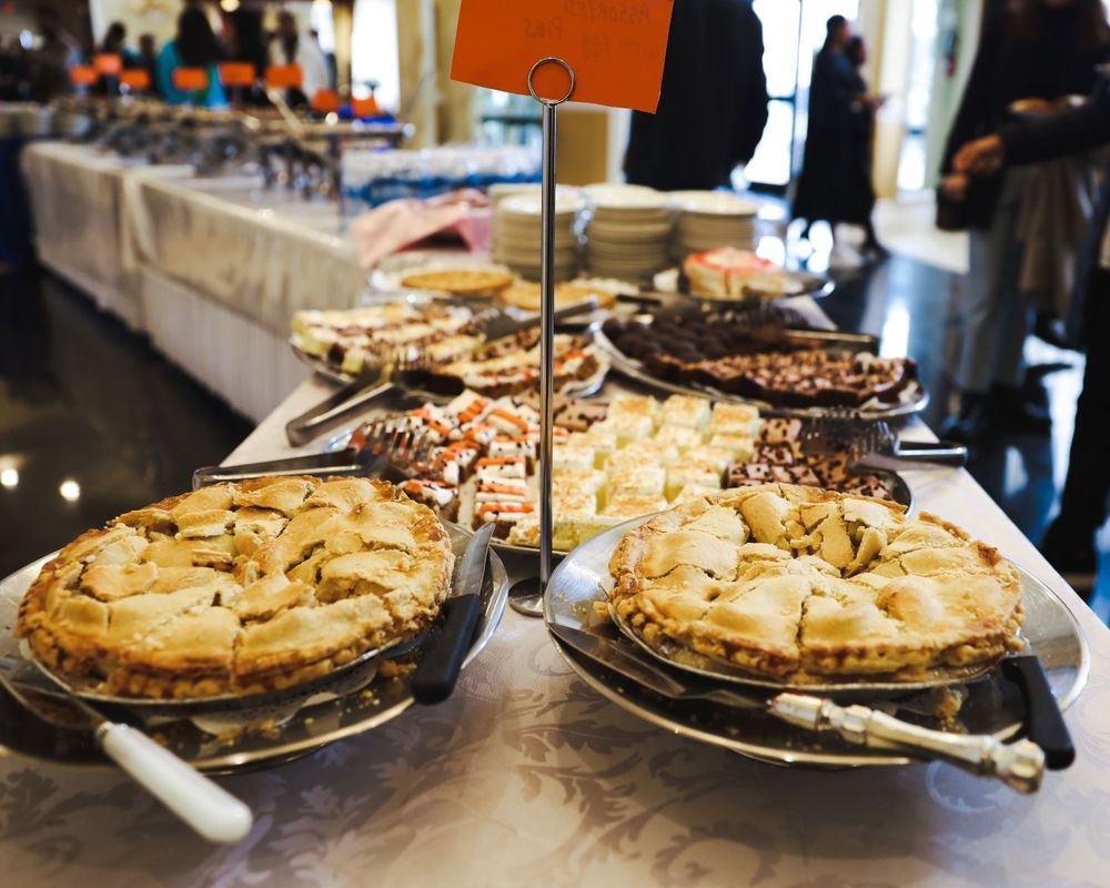 Array of freshly baked pies displayed on a buffet table at a catering event.