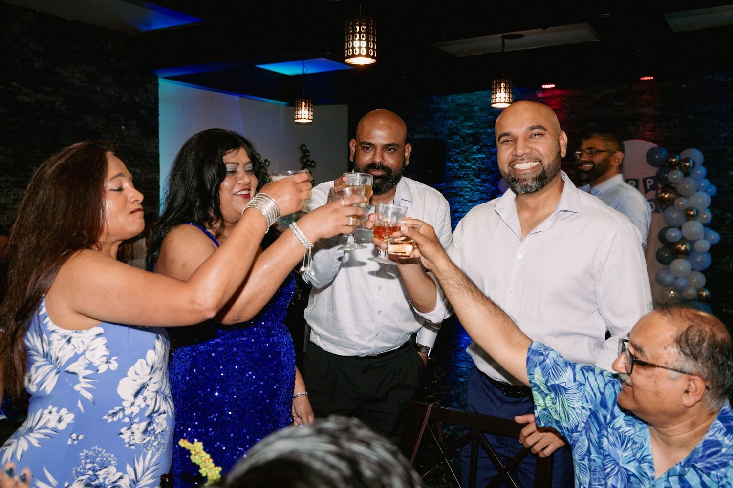 Group of friends toasting with drinks at a festive party celebration indoors.