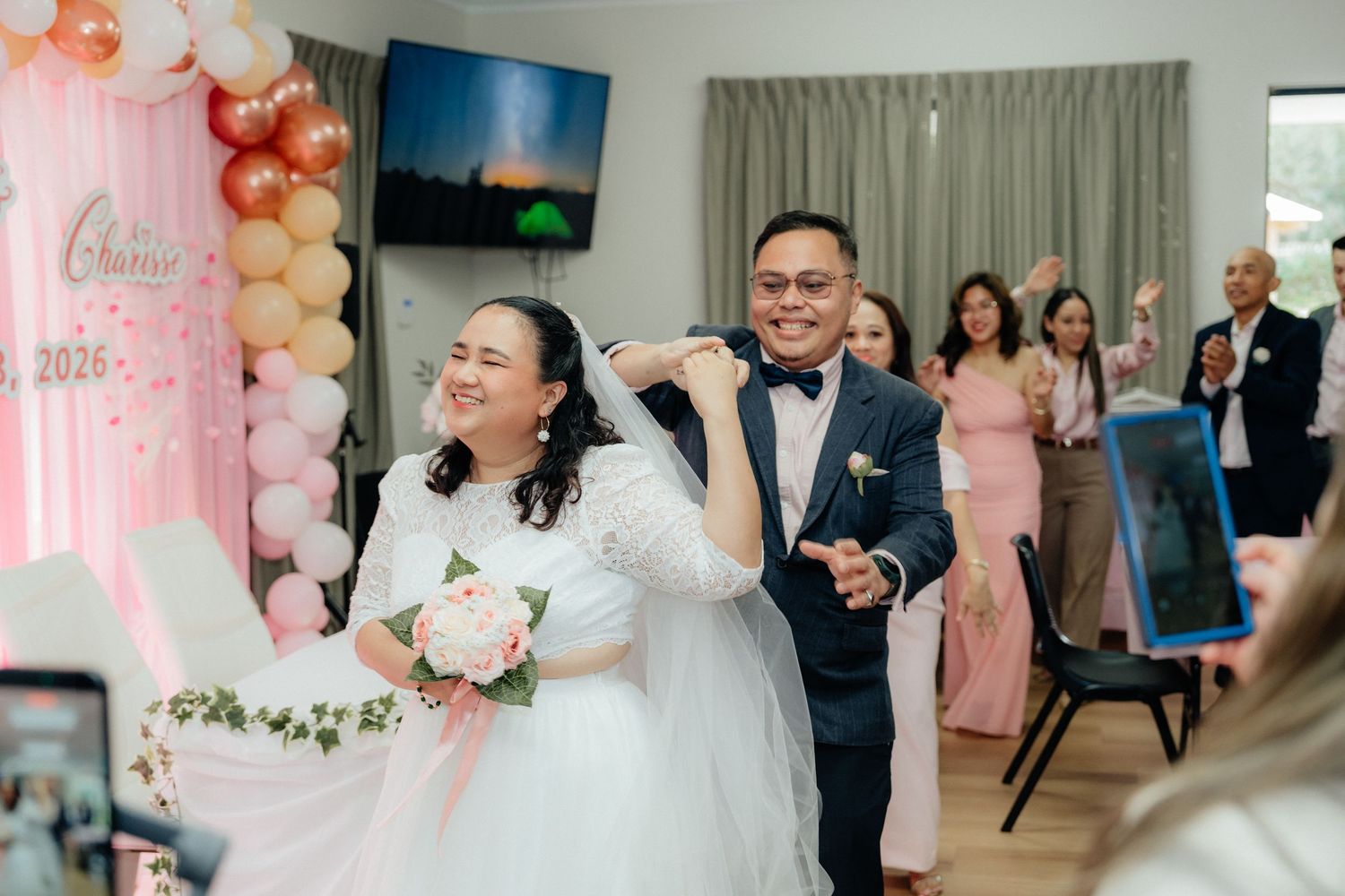 A joyful bride and groom make their grand entrance at their wedding reception celebration.