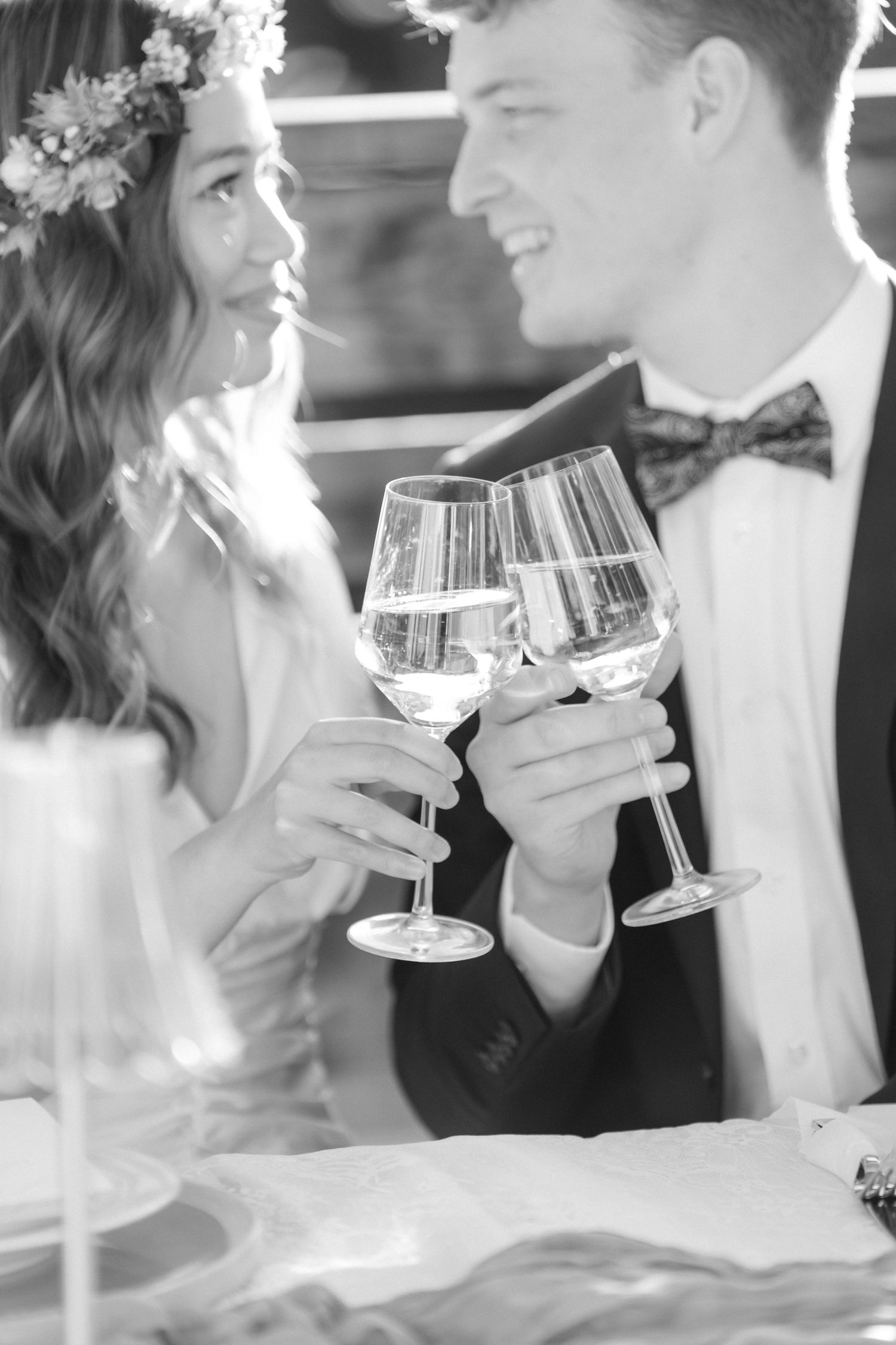 Black and white photo of bride and groom toasting with champagne glasses at their wedding reception.