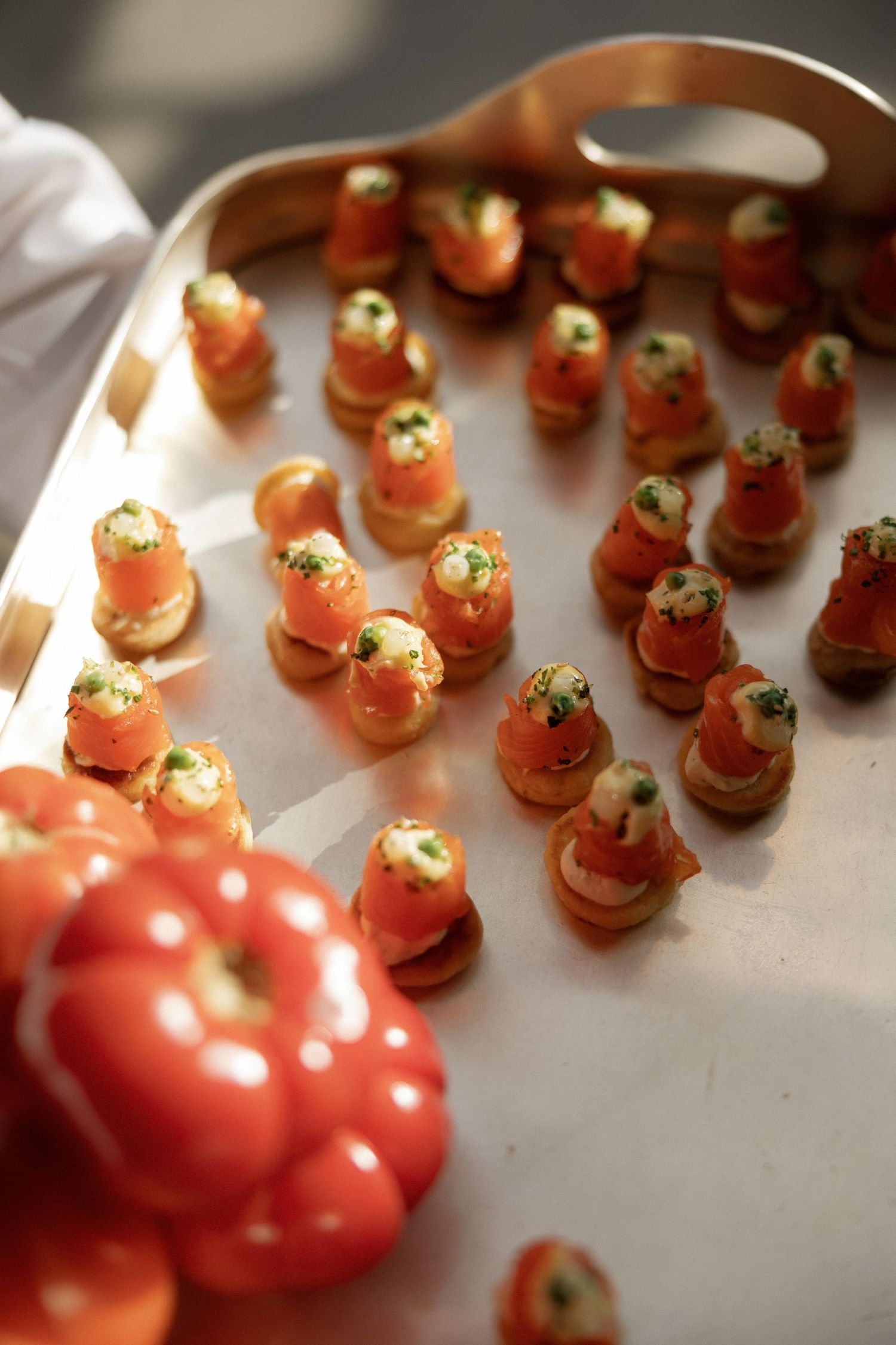 Elegant smoked salmon canapes with cream cheese on crackers arranged on a silver serving tray at a catered event.