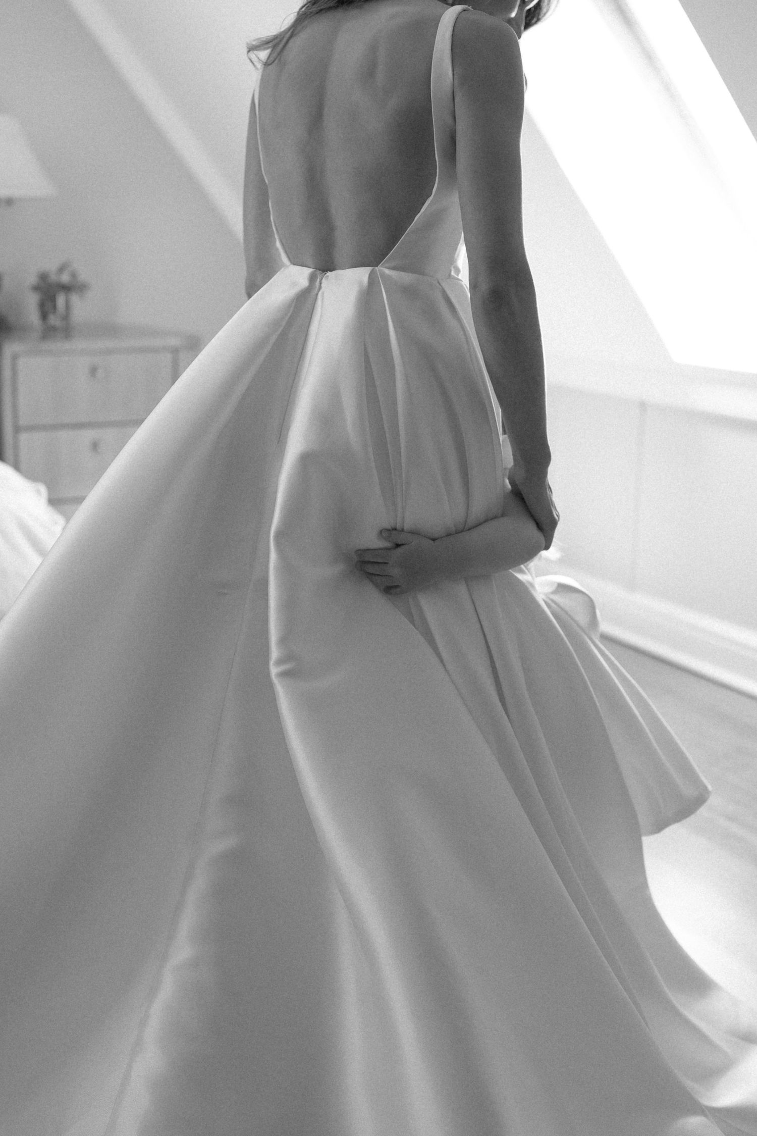 Elegant backless white wedding gown with full skirt, captured in black and white photography.