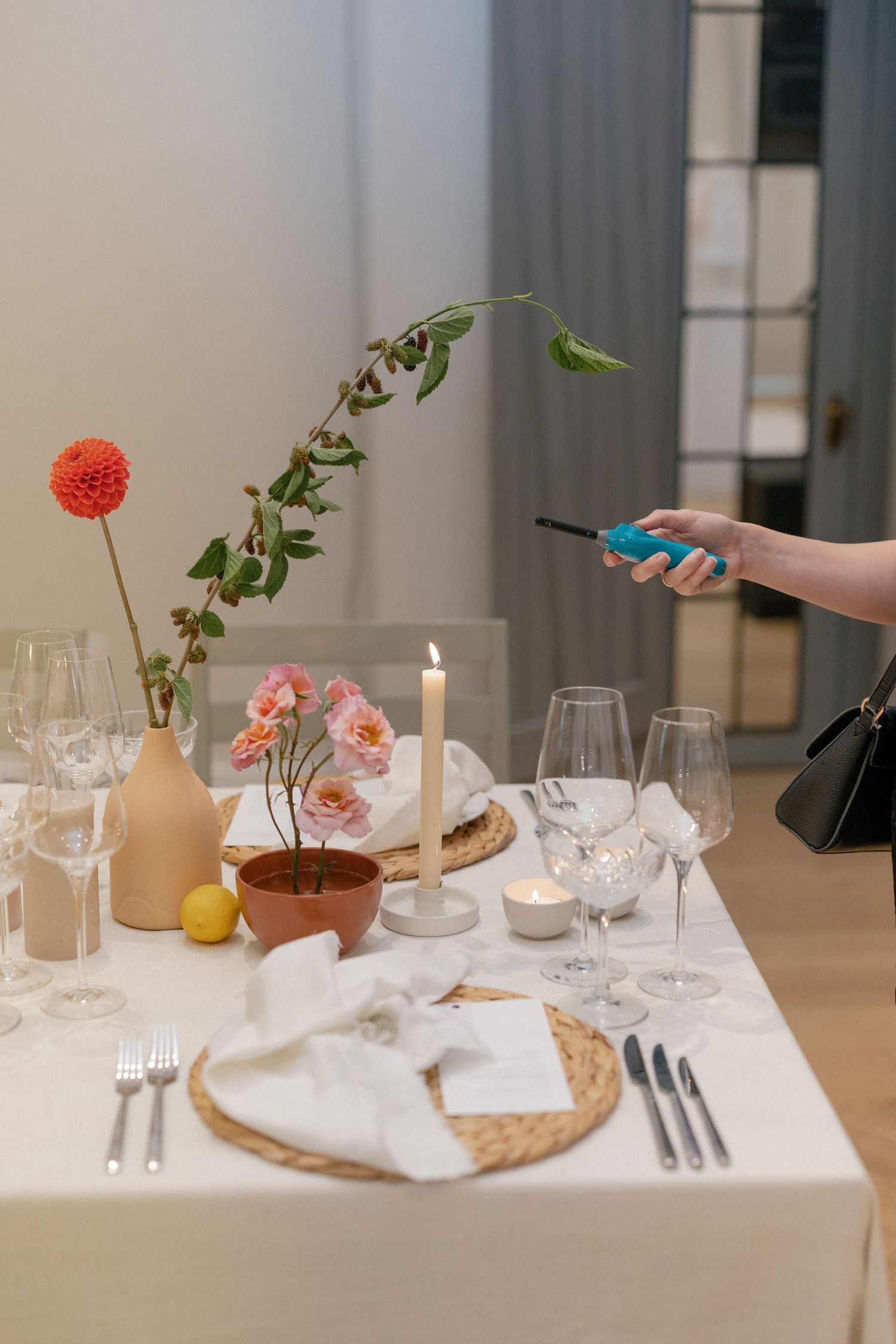Wedding table setting with flowers in terracotta vases, candles, and crystal glassware being photographed.