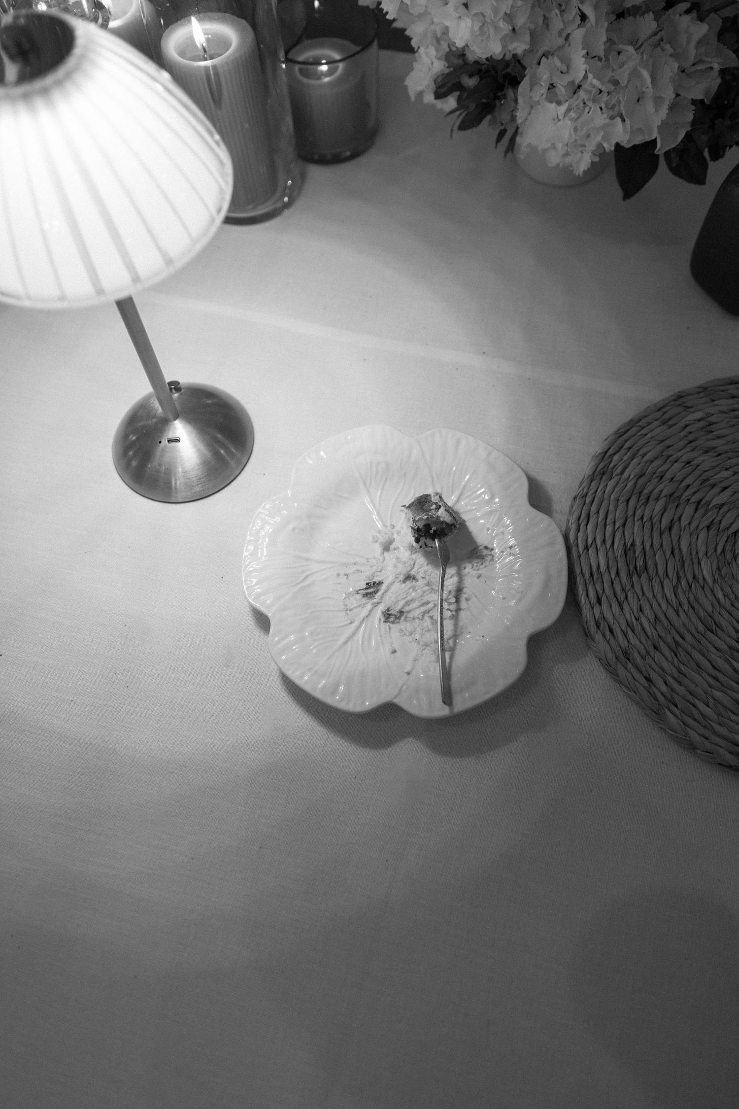 Black and white wedding table decor with small lamp, candles, flower plate, and hydrangeas.