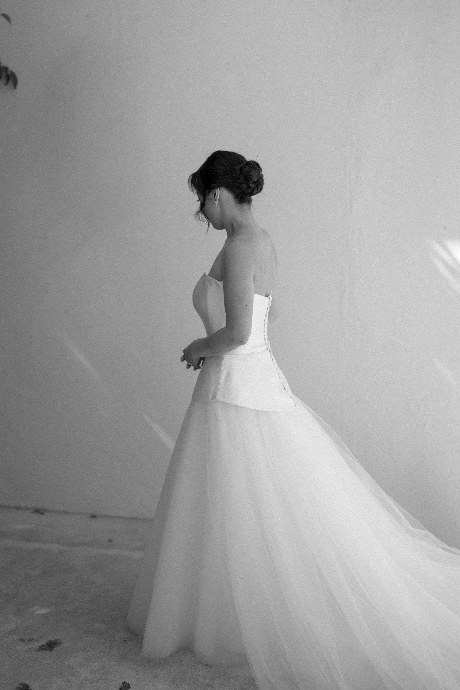 Black and white photo of a bride in a strapless corset wedding gown with tulle skirt, hair in elegant updo.