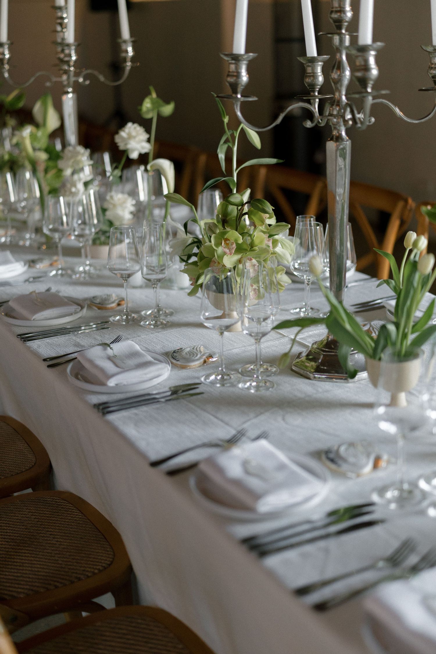 Elegant wedding reception table set with white linens, silver candelabras, tulips, and crystal glassware.