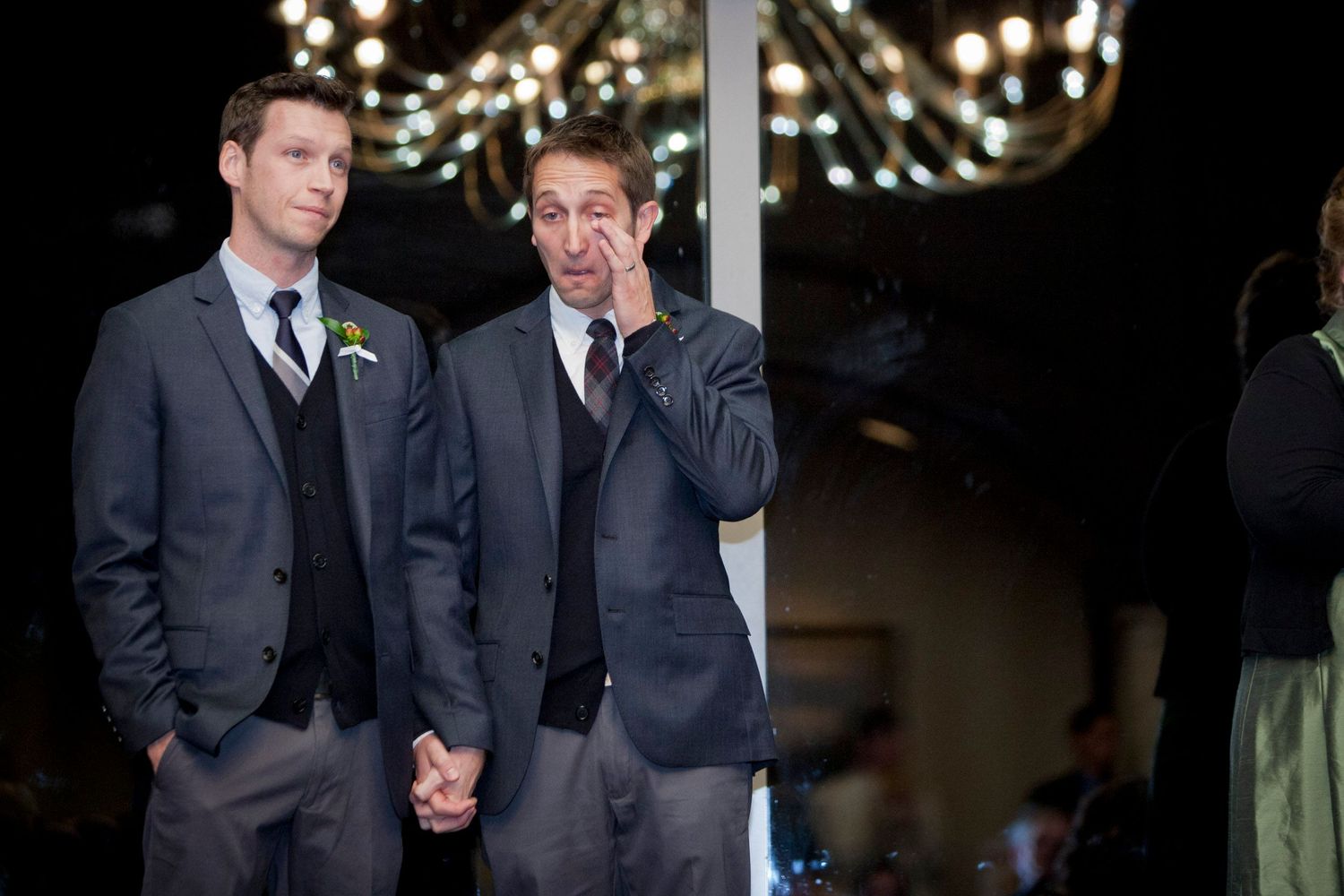 Two men in matching gray suits standing together at a wedding reception.