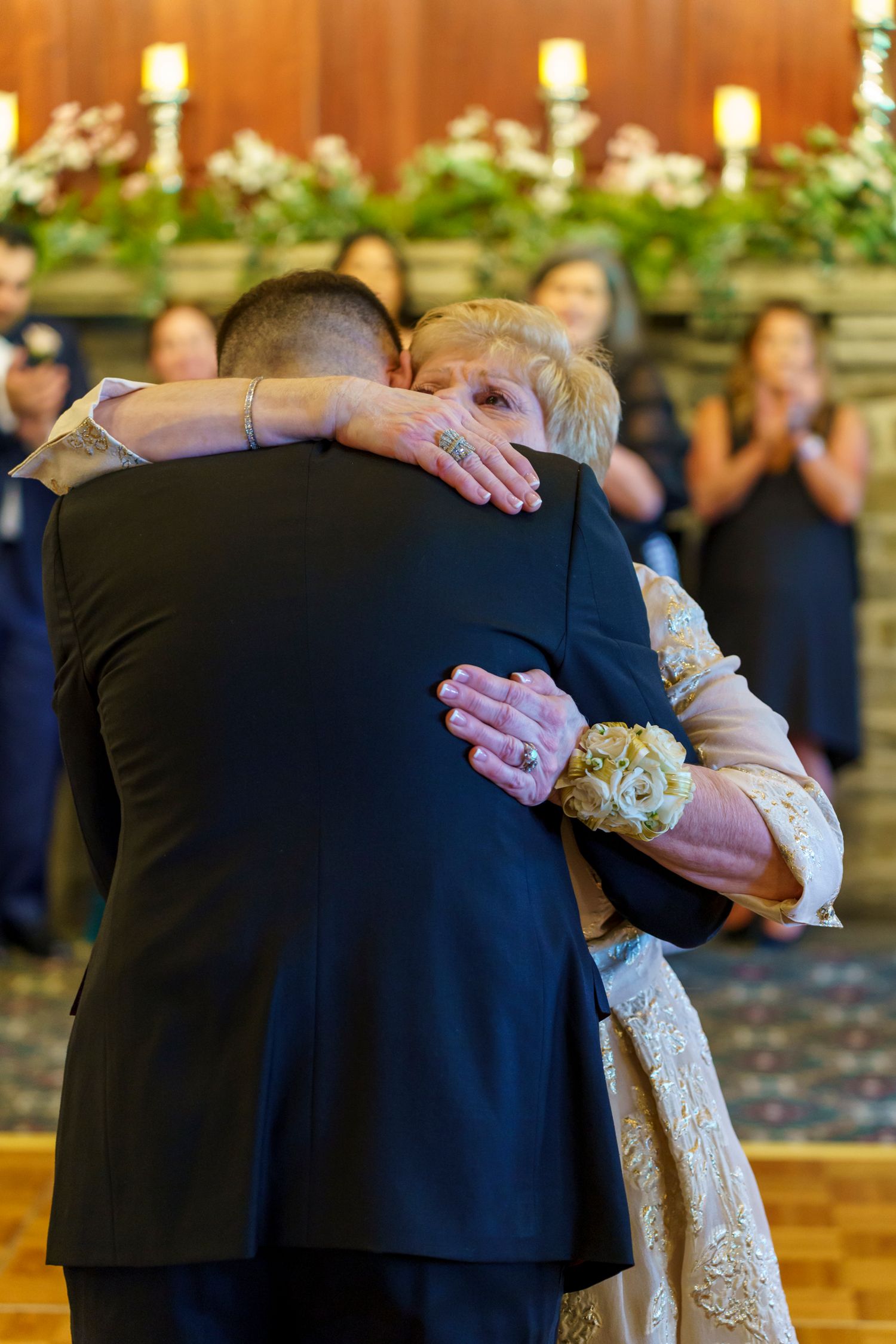 Emotional mother and son dance at wedding reception, sharing a heartfelt hug on the dance floor.
