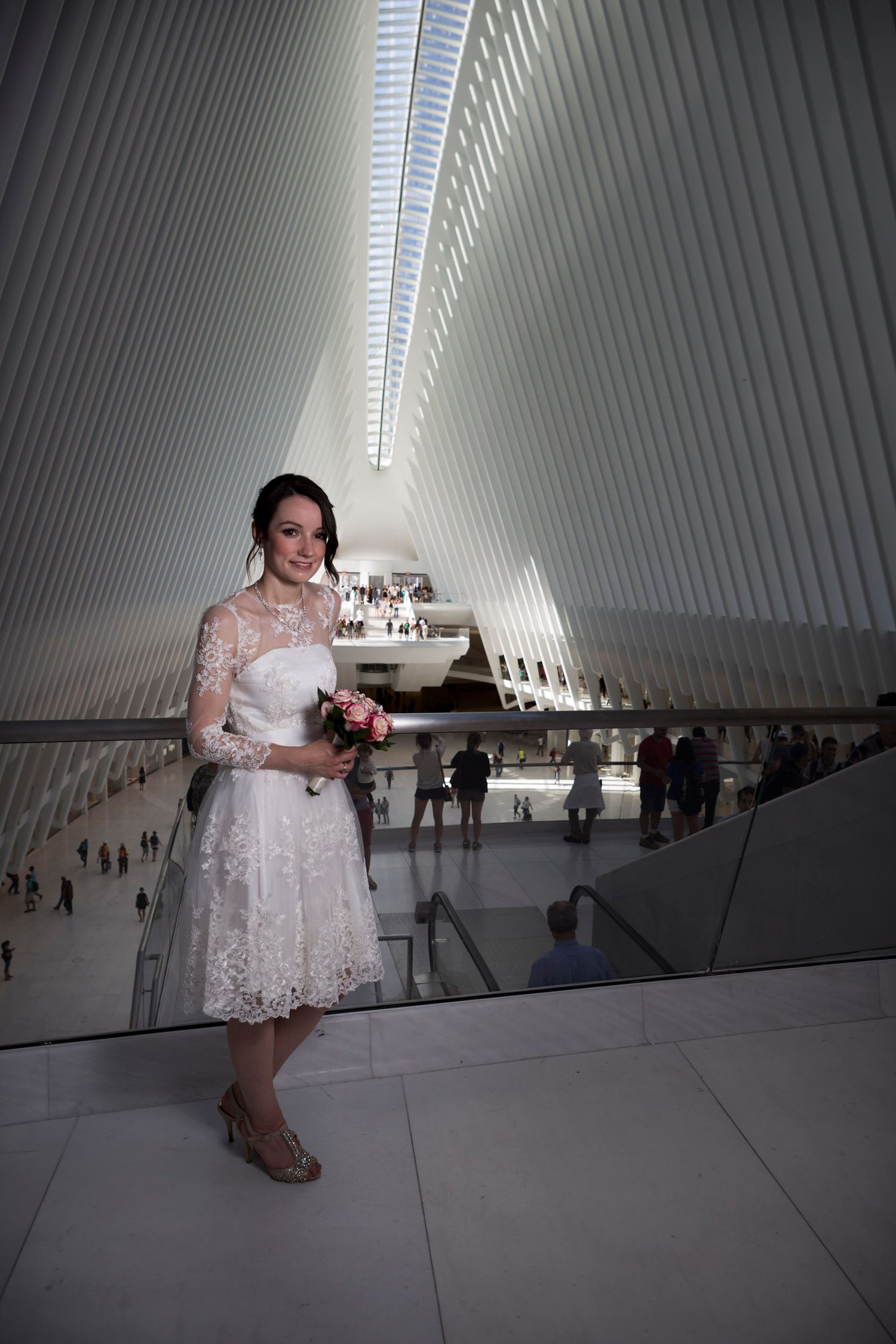 Bride in white lace dress holds bouquet inside the Oculus at World Trade Center, NYC.
