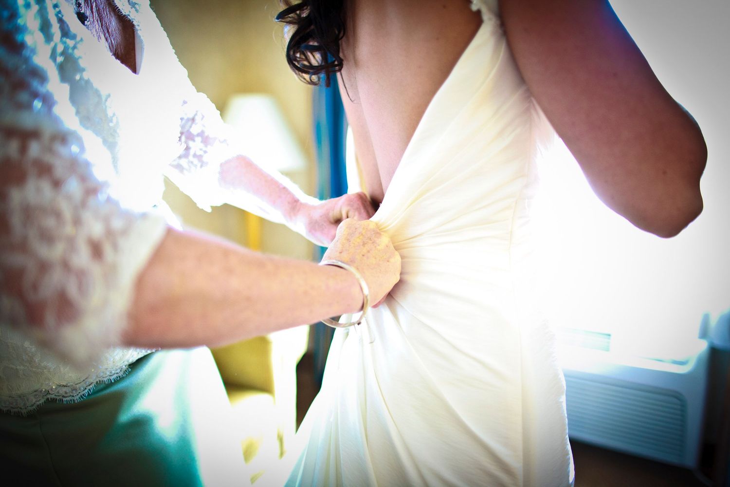 A bride getting her wedding dress fastened by a helper before the ceremony.