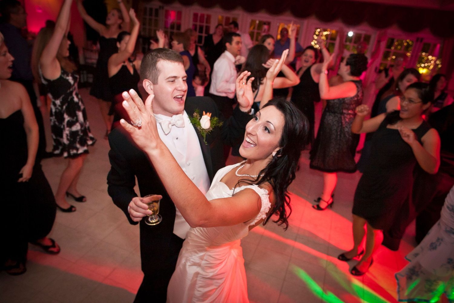 Bride and groom dancing joyfully with guests at lively wedding reception party.