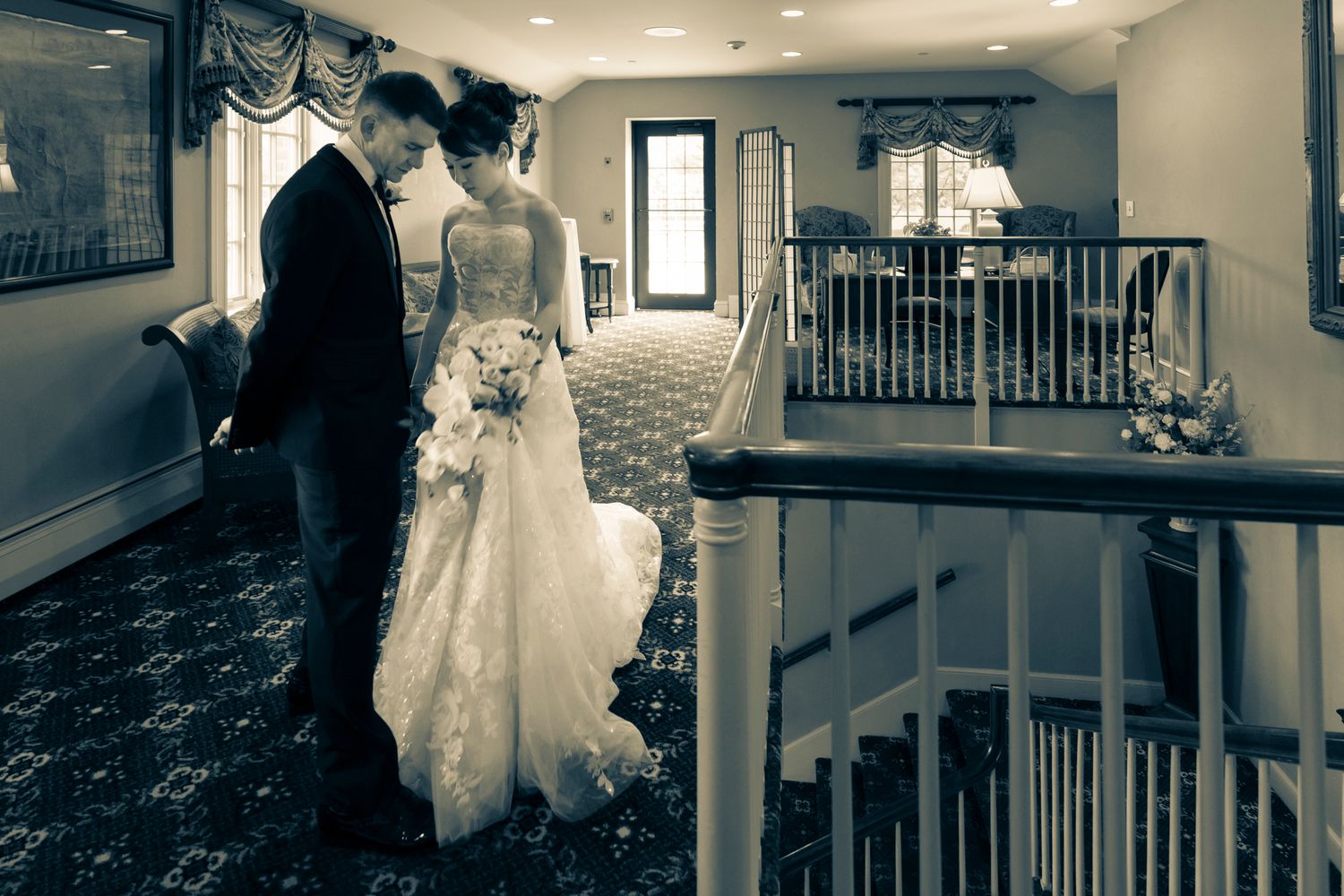 Bride and groom share quiet moment on elegant staircase in black and white.