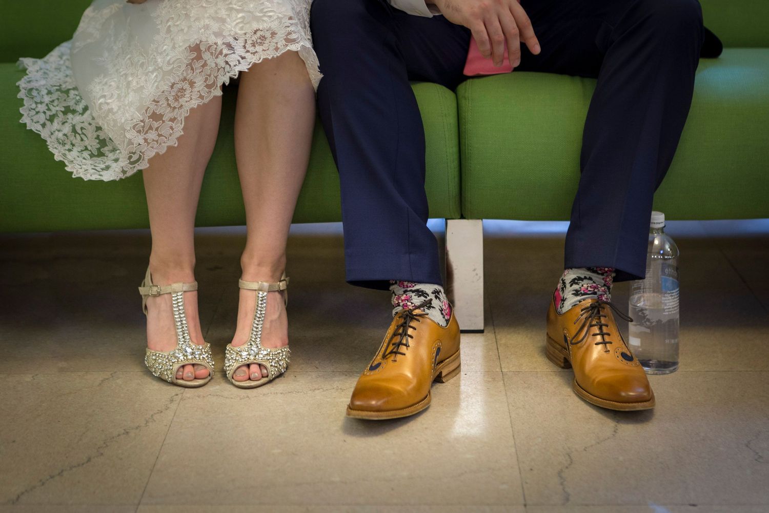 Bride and groom sitting together showing colorful patterned socks and vintage wedding shoes.