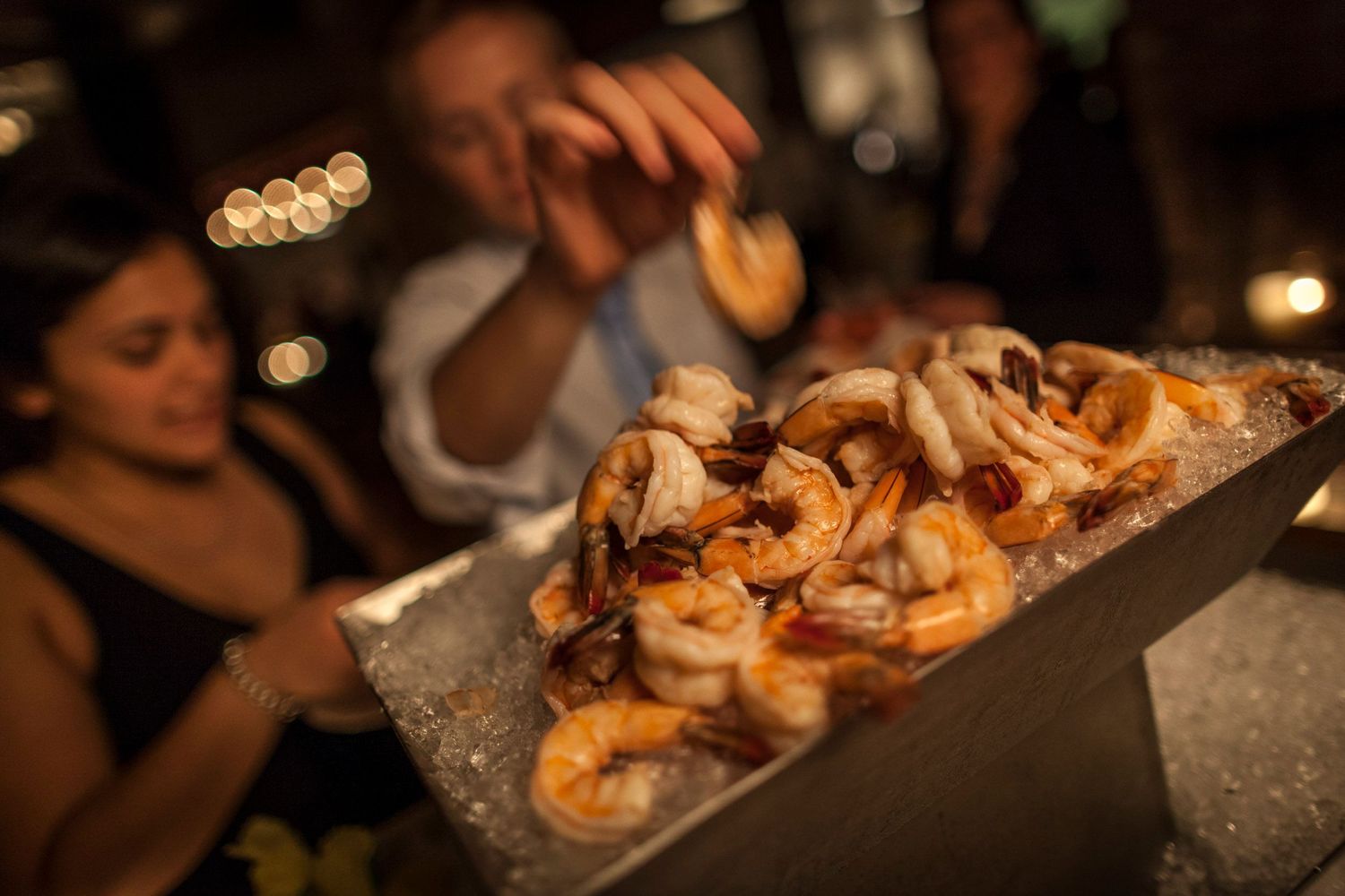 A tray of fresh shrimp cocktail on ice served at an elegant evening event.