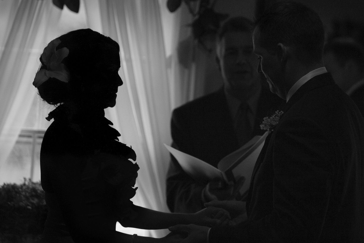 Dramatic black and white silhouette of a bride and groom exchanging vows at the altar.