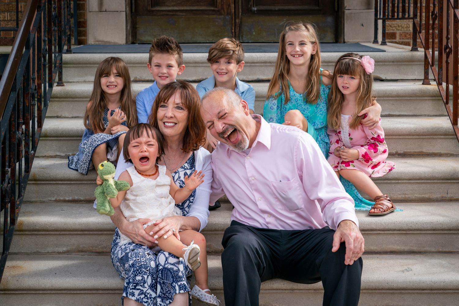 Happy family with six children posing together on outdoor stone steps.